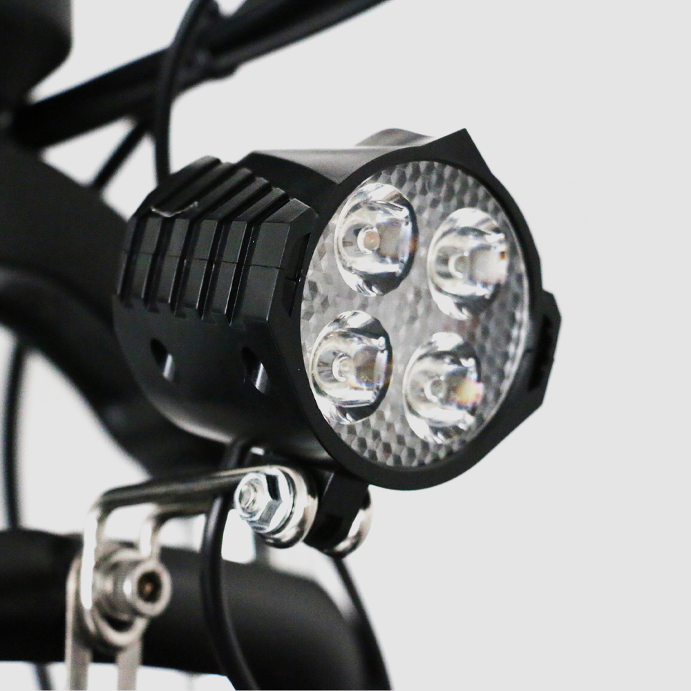 Czarny przedni reflektor rowerowy z czterema diodami LED, zamontowany na ramie roweru.