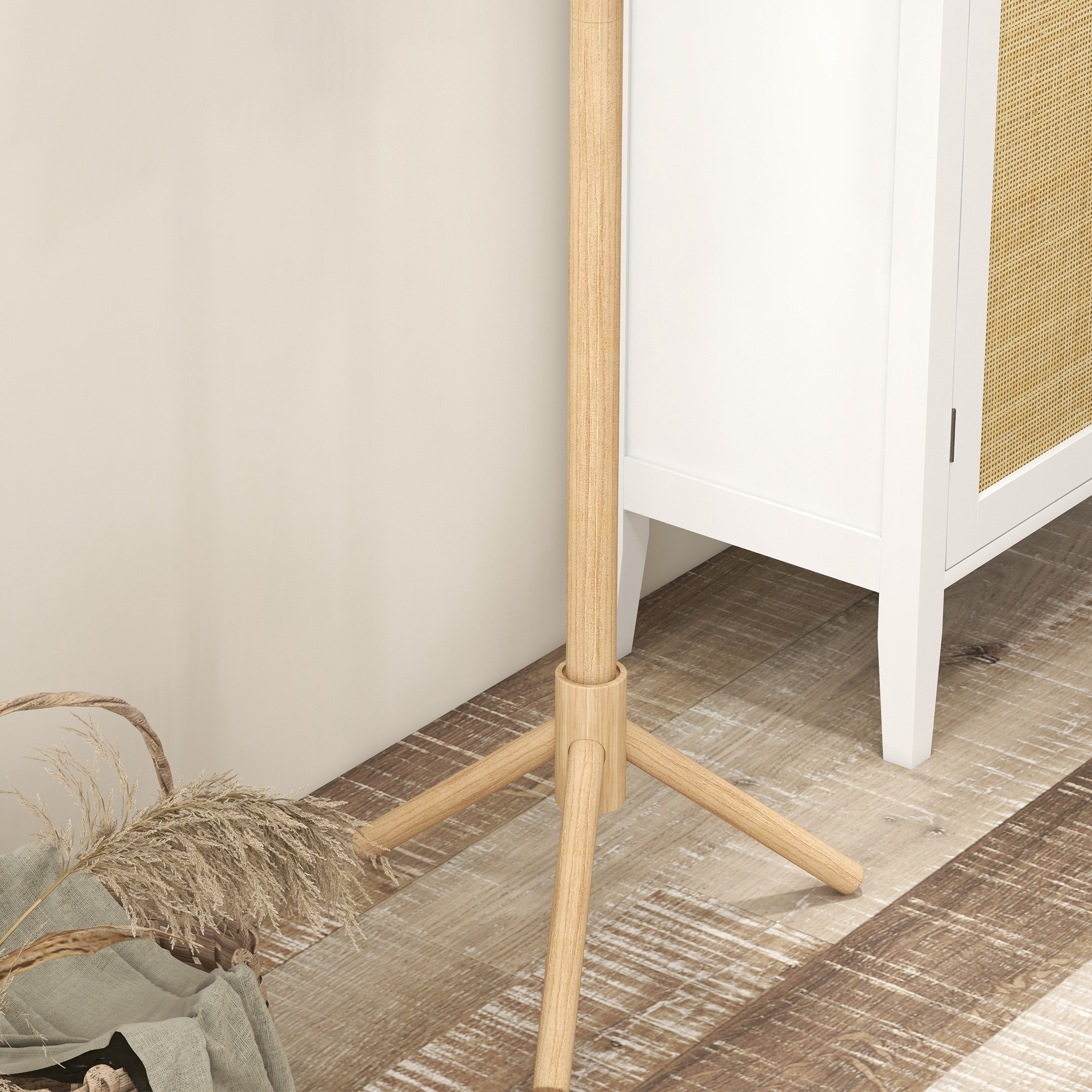 Soporte de trípode de madera junto a un armario blanco con puerta de ratán.