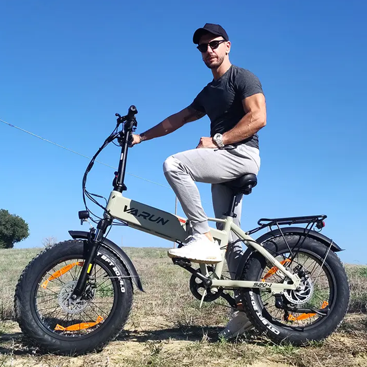 Mężczyzna na jasnozielonym rowerze elektrycznym z grubymi oponami na zewnątrz.