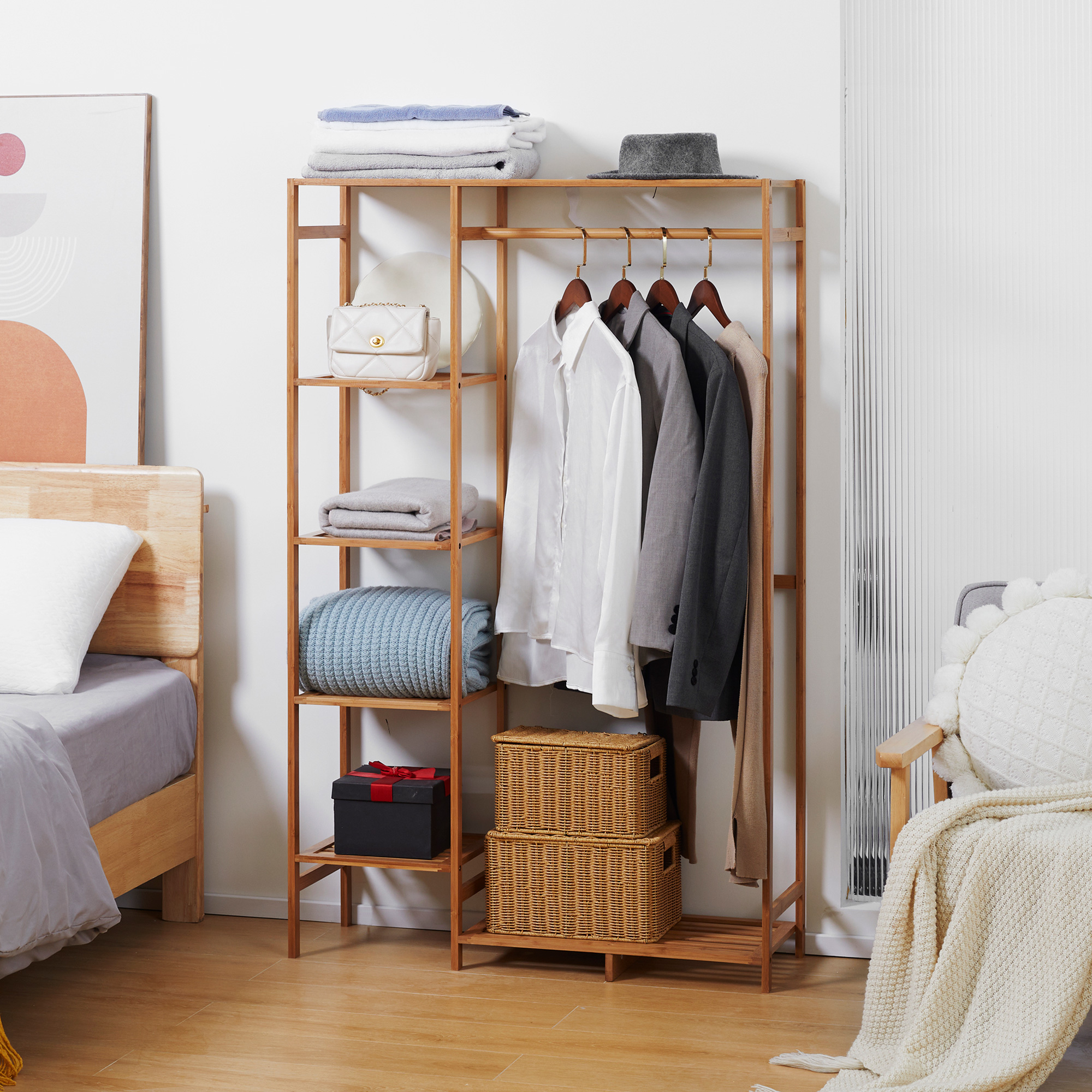 Un tendedero de madera con ropa, bolsos y cestas junto a una cama.