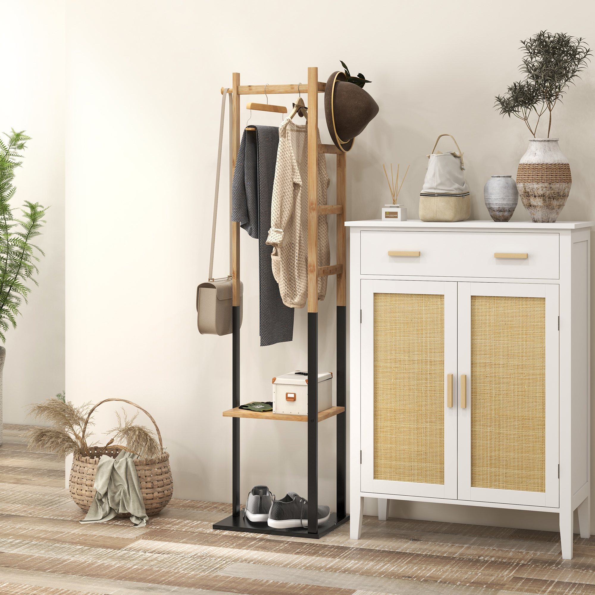 Un perchero de madera con ropa, sombrero y bolso junto a un armario blanco.