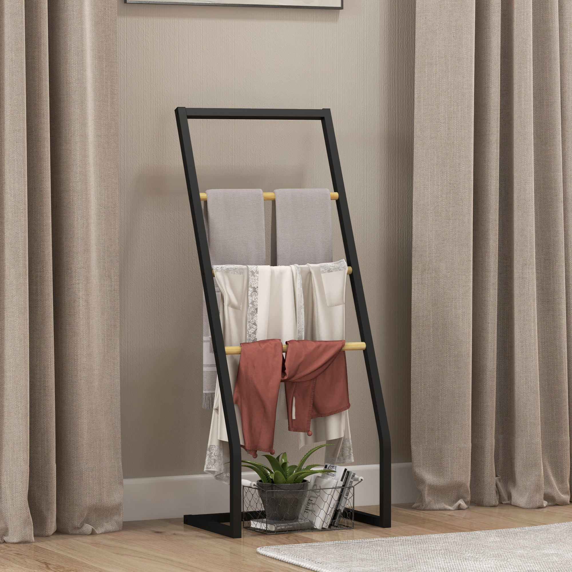 Un porta asciugamani a scala nero con coperte grigie e crema, sciarpe ruggine, pianta e libri.