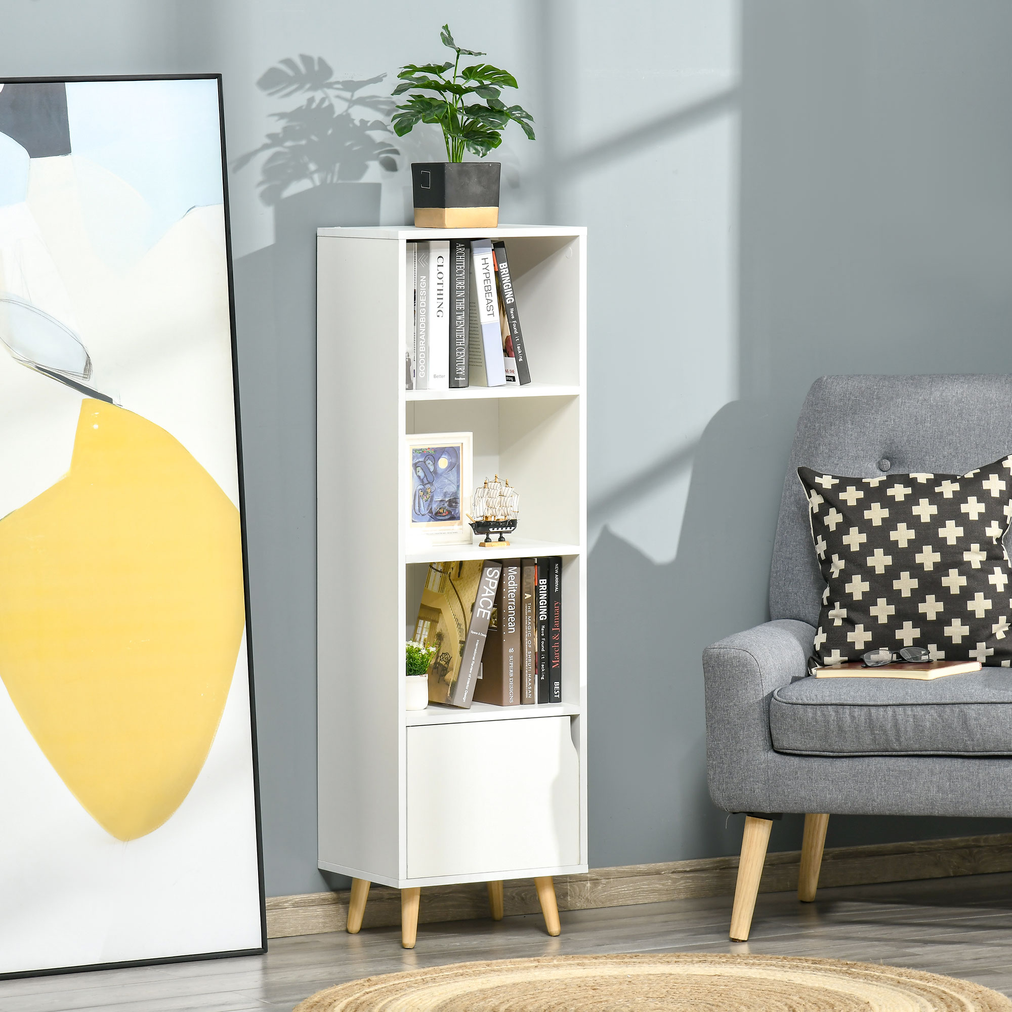 Una estantería blanca con libros, una planta y un sillón al lado.