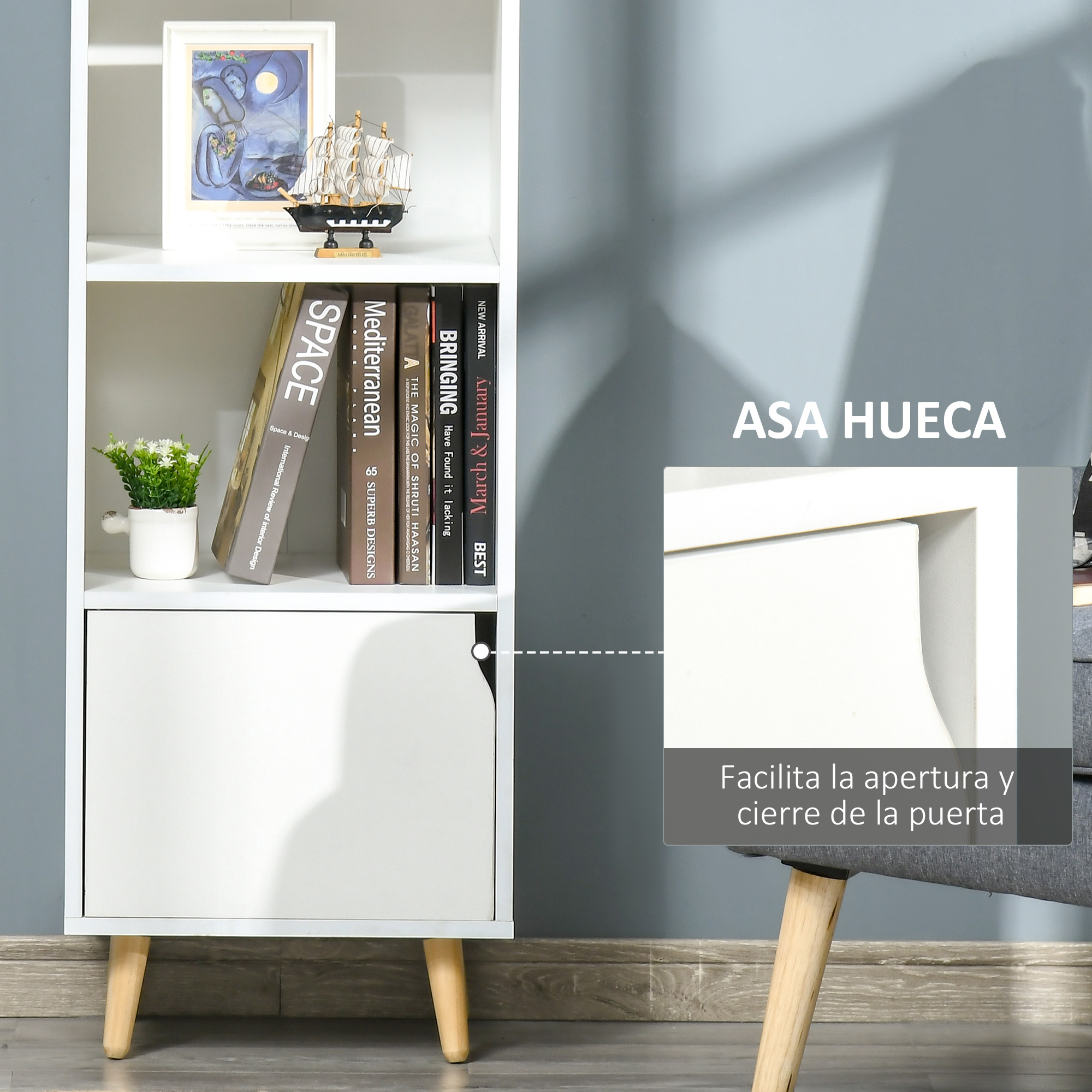 Un estante blanco con libros, planta en maceta, modelo de barco y obra de arte.