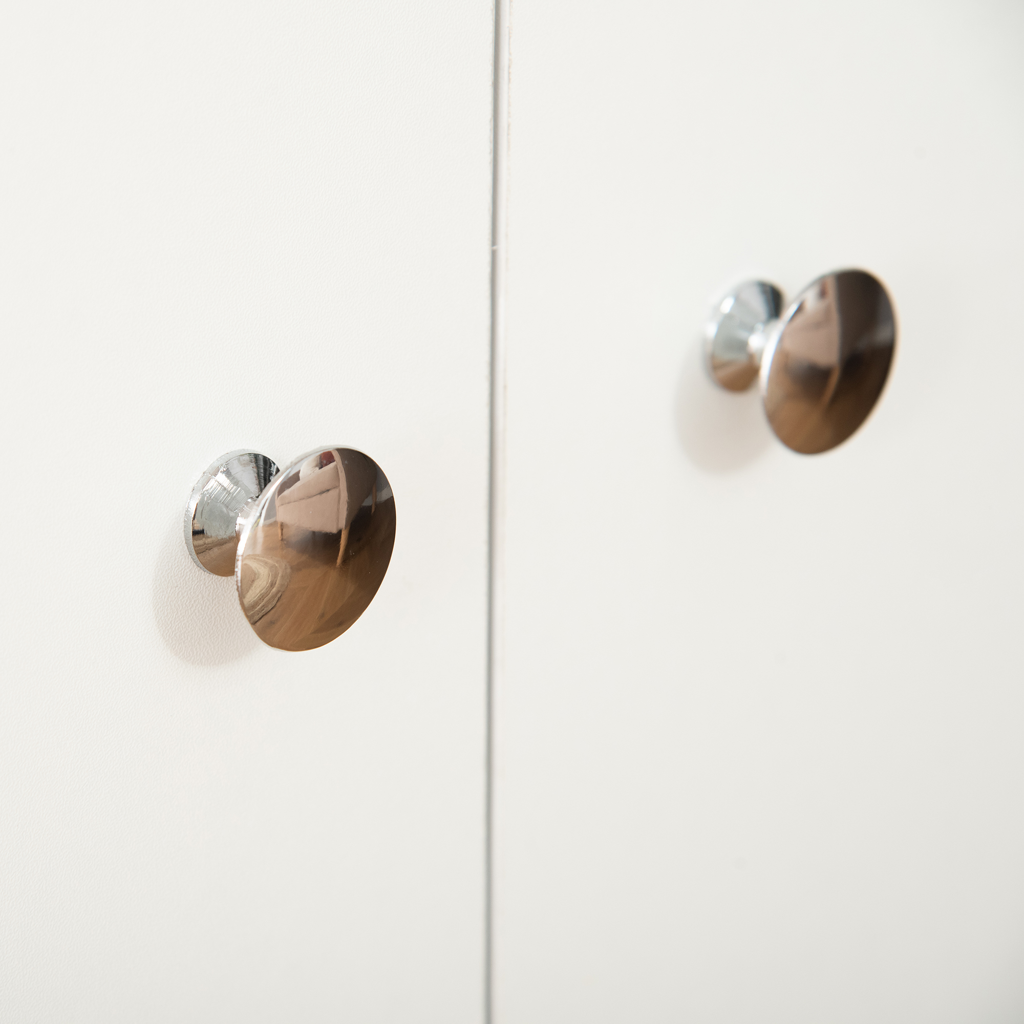 Dos tiradores plateados brillantes en una puerta blanca.