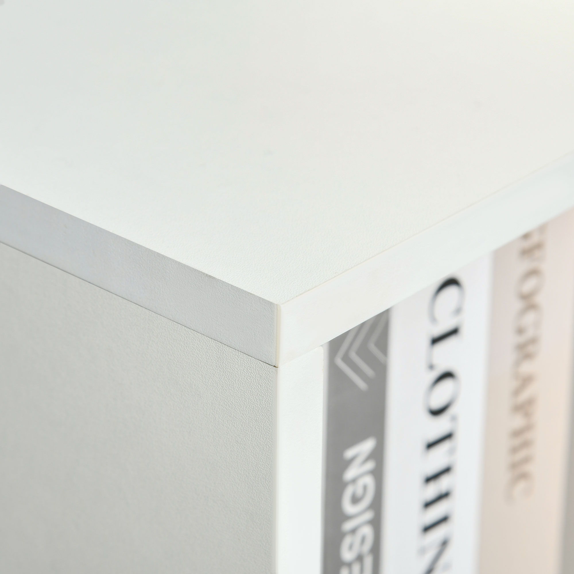 Primer plano de un estante blanco con libros que muestran 'DESIGN', 'CLOTHIN' y 'FOGRAPHIC'.