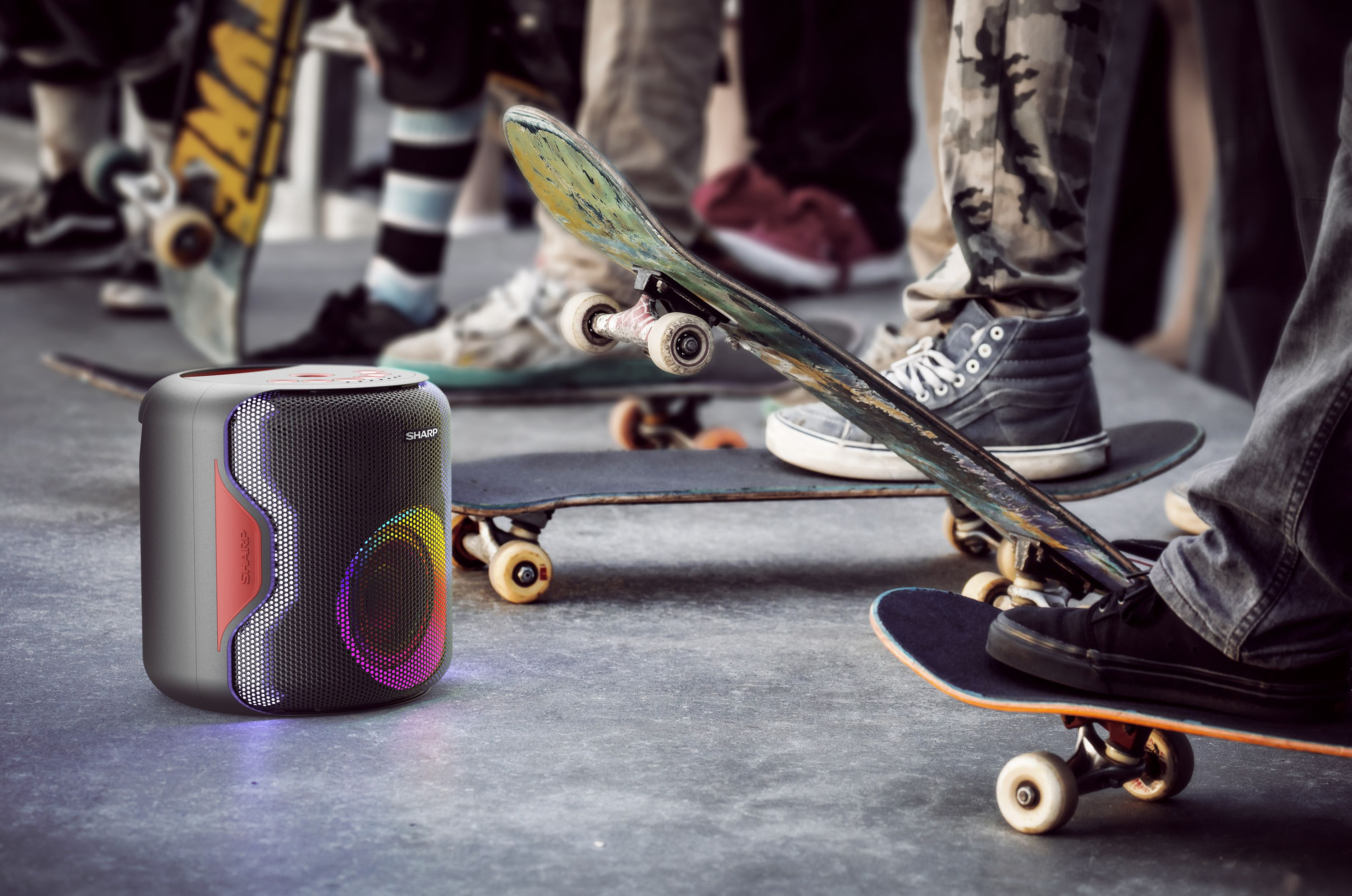 Ein tragbarer Lautsprecher mit bunten Lichtern steht neben Skateboardern.