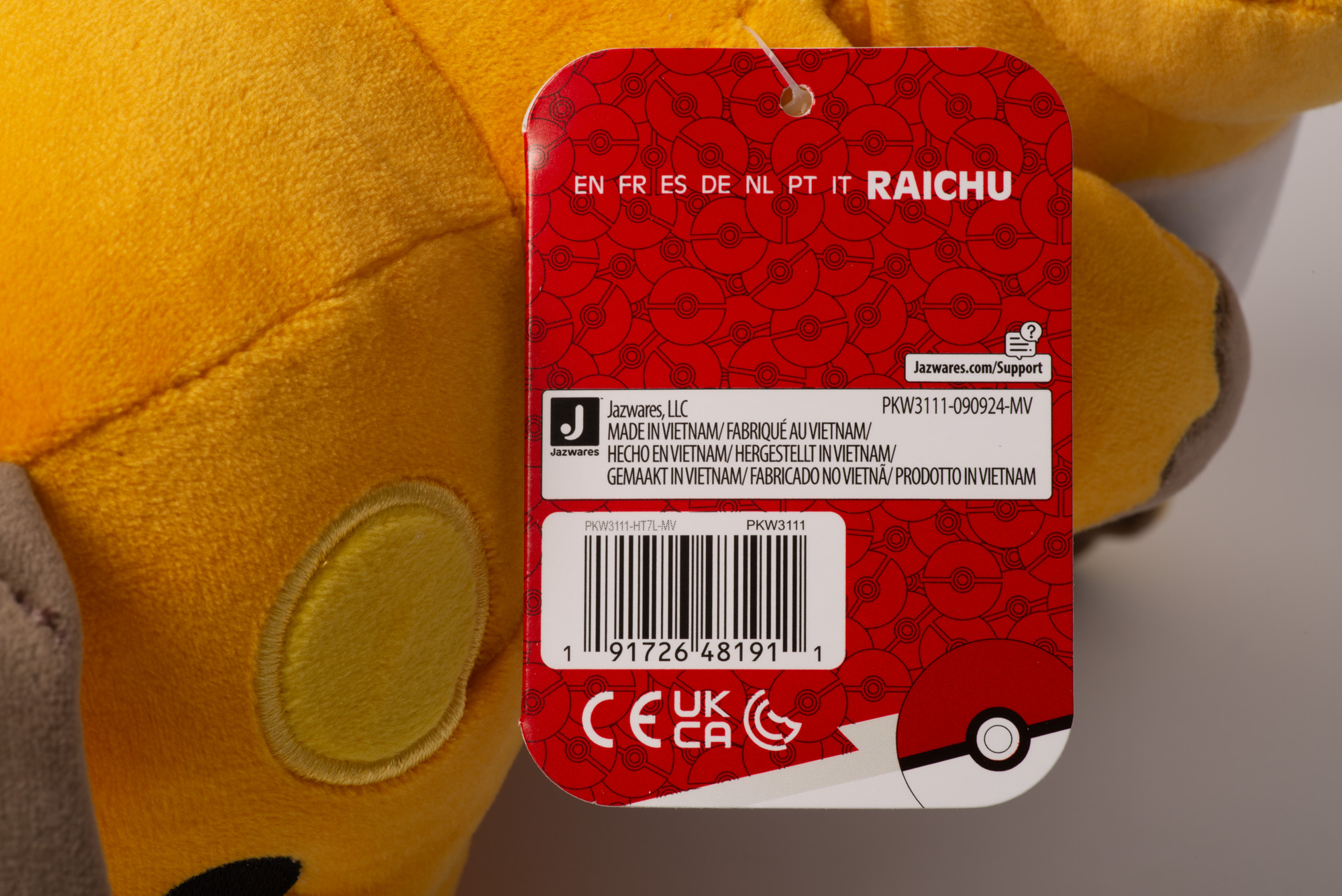 Ein gelbes Plüschtier mit einem roten Etikett, das 'Raichu' und einen Barcode zeigt.