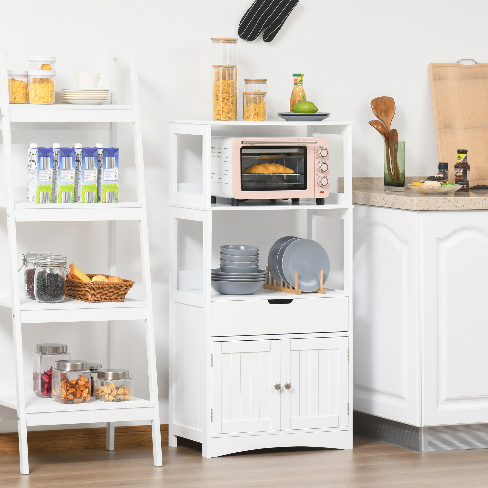 Una unidad de estantería de cocina blanca con horno rosa, vajilla y frascos.