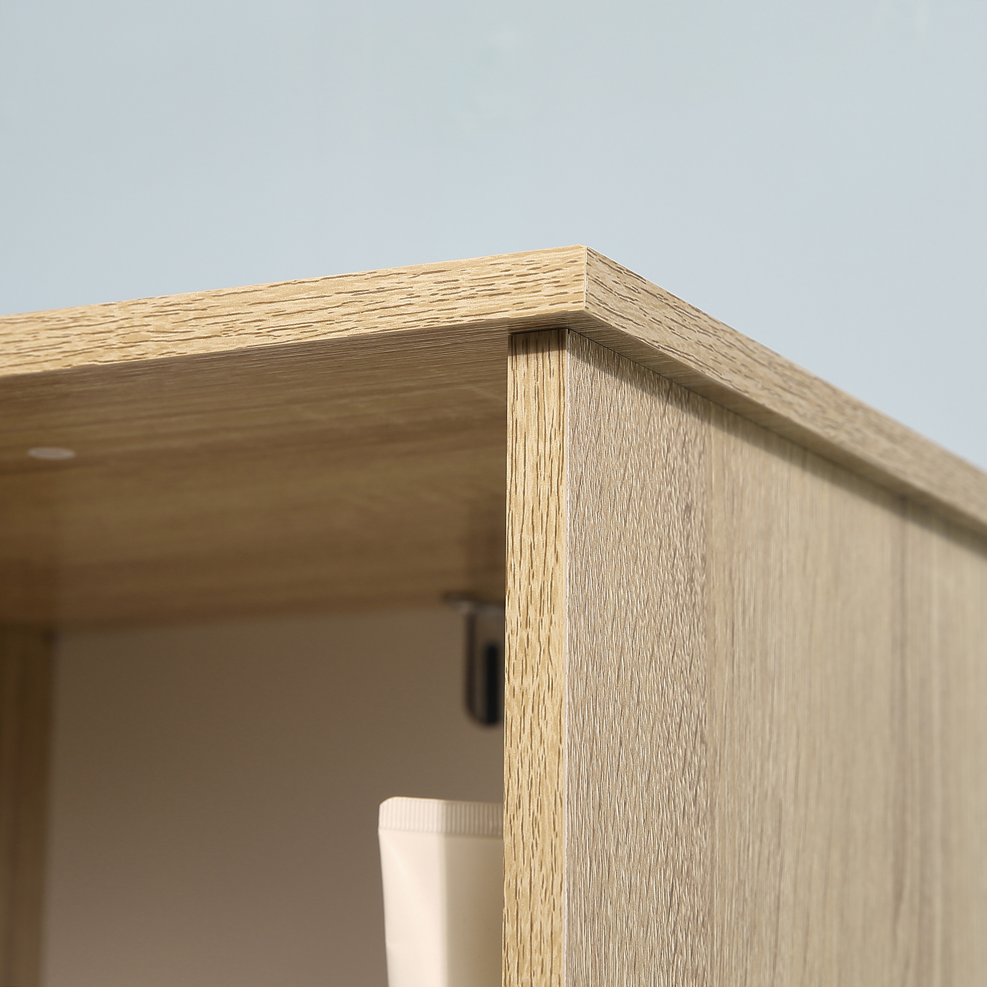Un armario de madera contra un fondo azul claro. Se ve un tubo blanco.