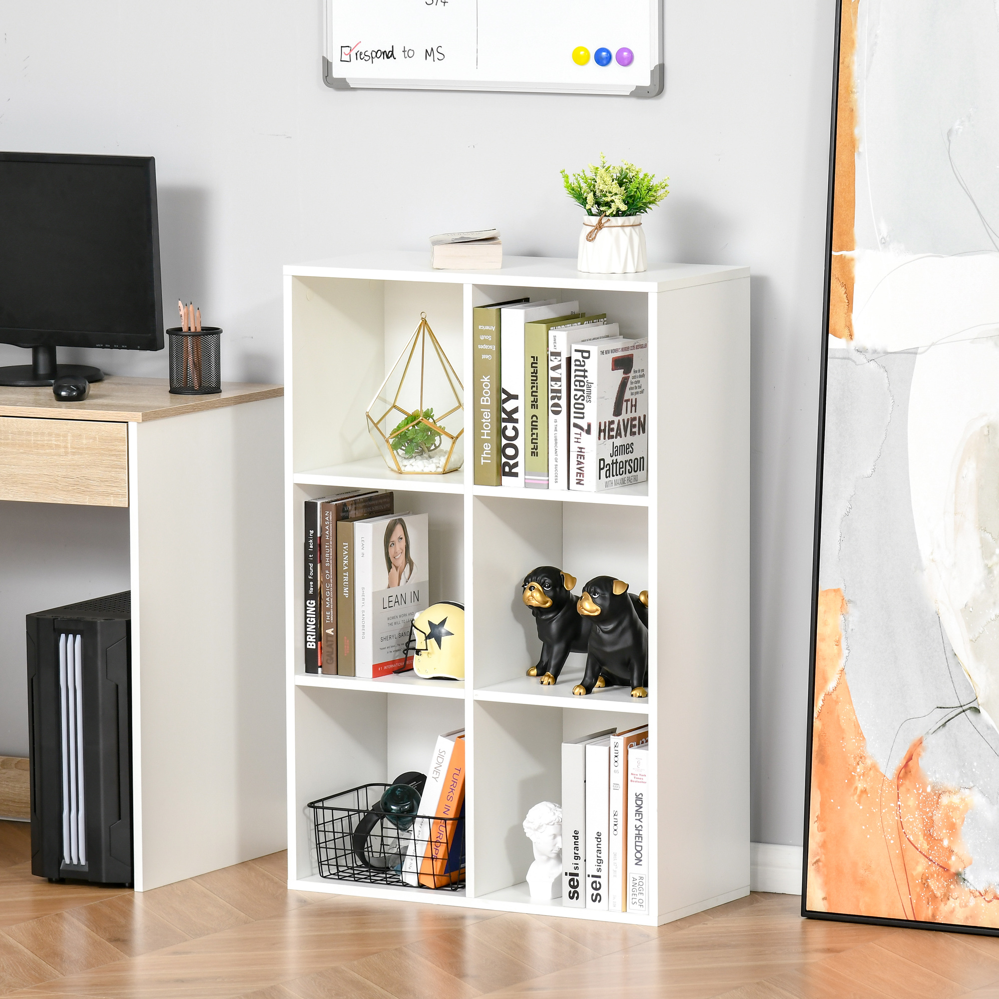 Una libreria bianca con libri, decorazioni e un computer su una scrivania.