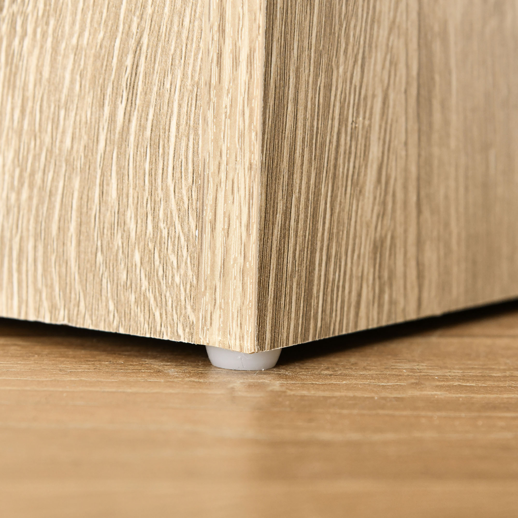 Patrón de veta de madera en mueble con pie blanco sobre suelo de madera.