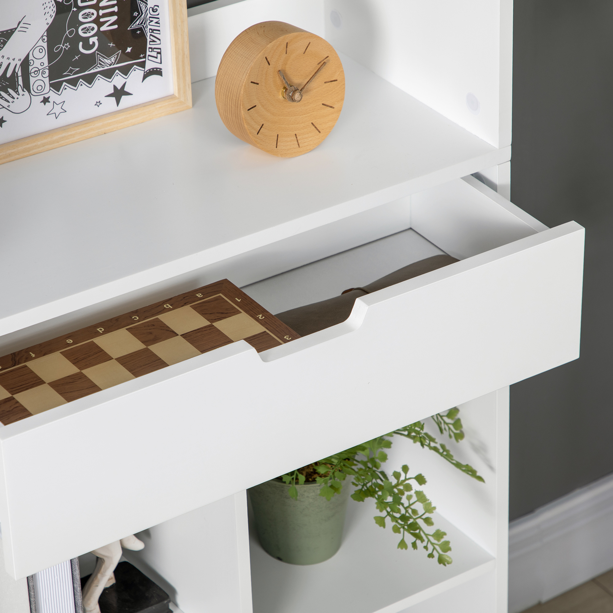 Reloj de madera y tablero de ajedrez en estante blanco. Un cuadro con impresión negra.