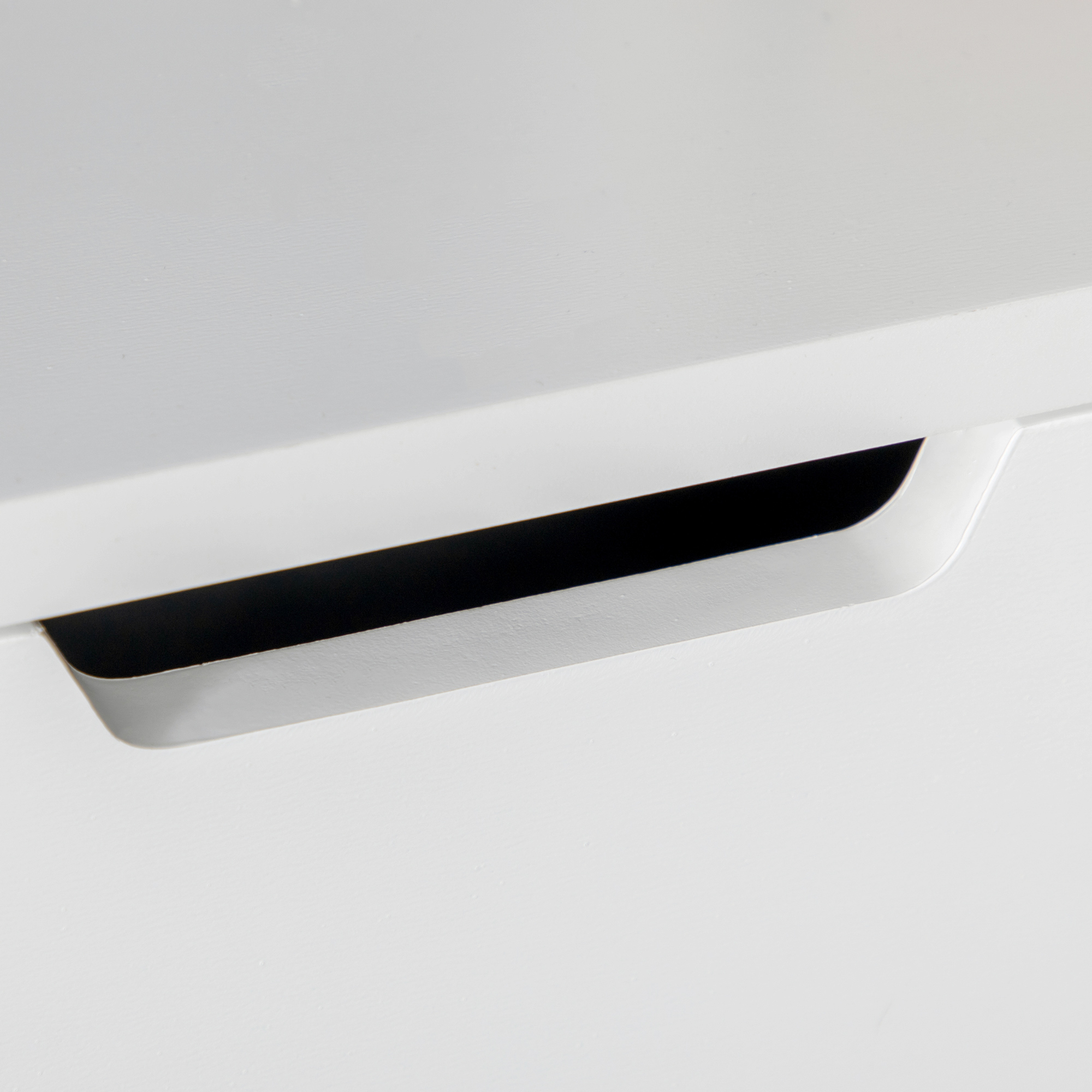 Primer plano de mueble blanco con un tirador empotrado estrecho y negro.