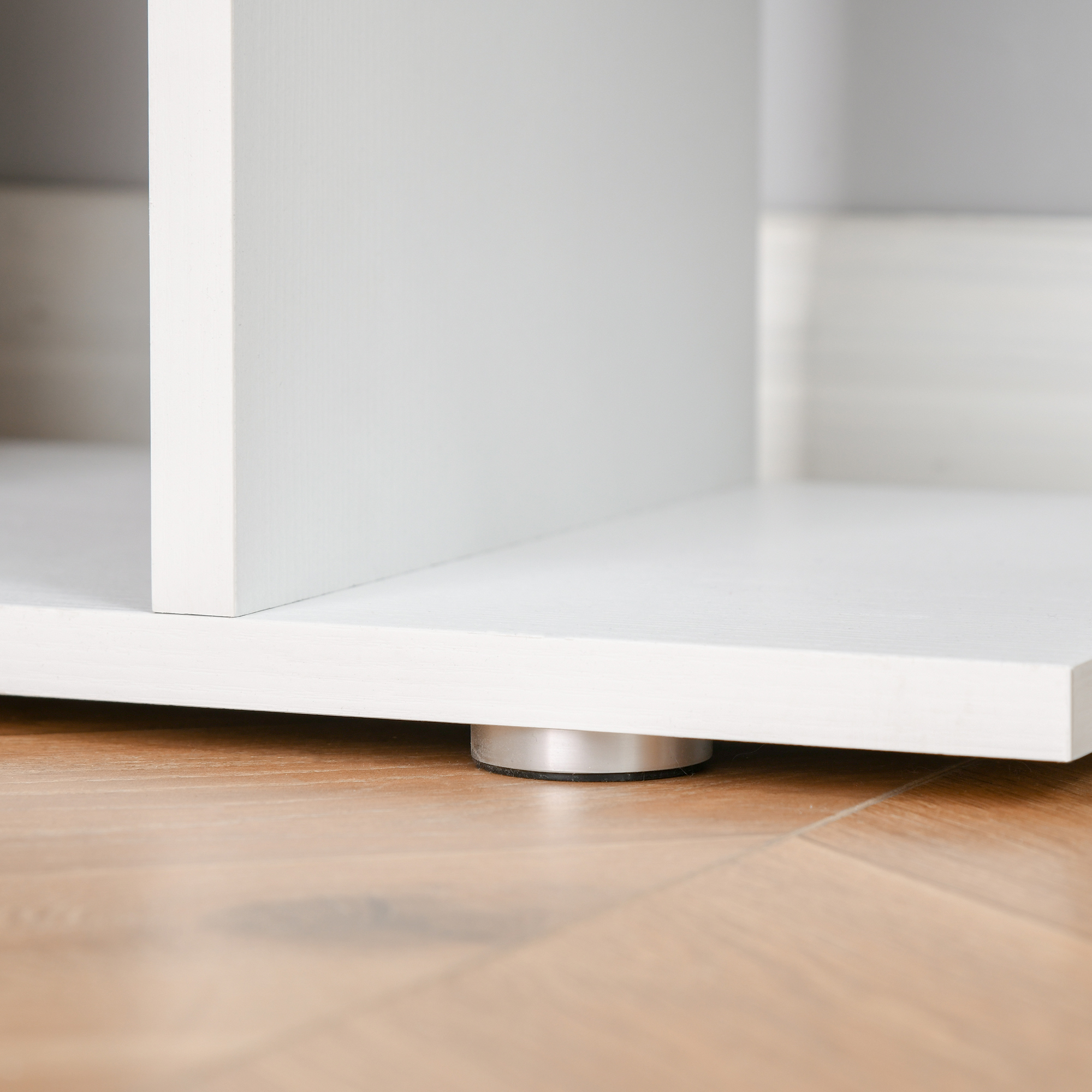 Primer plano de un mueble blanco sobre suelo de madera, con pata metálica.