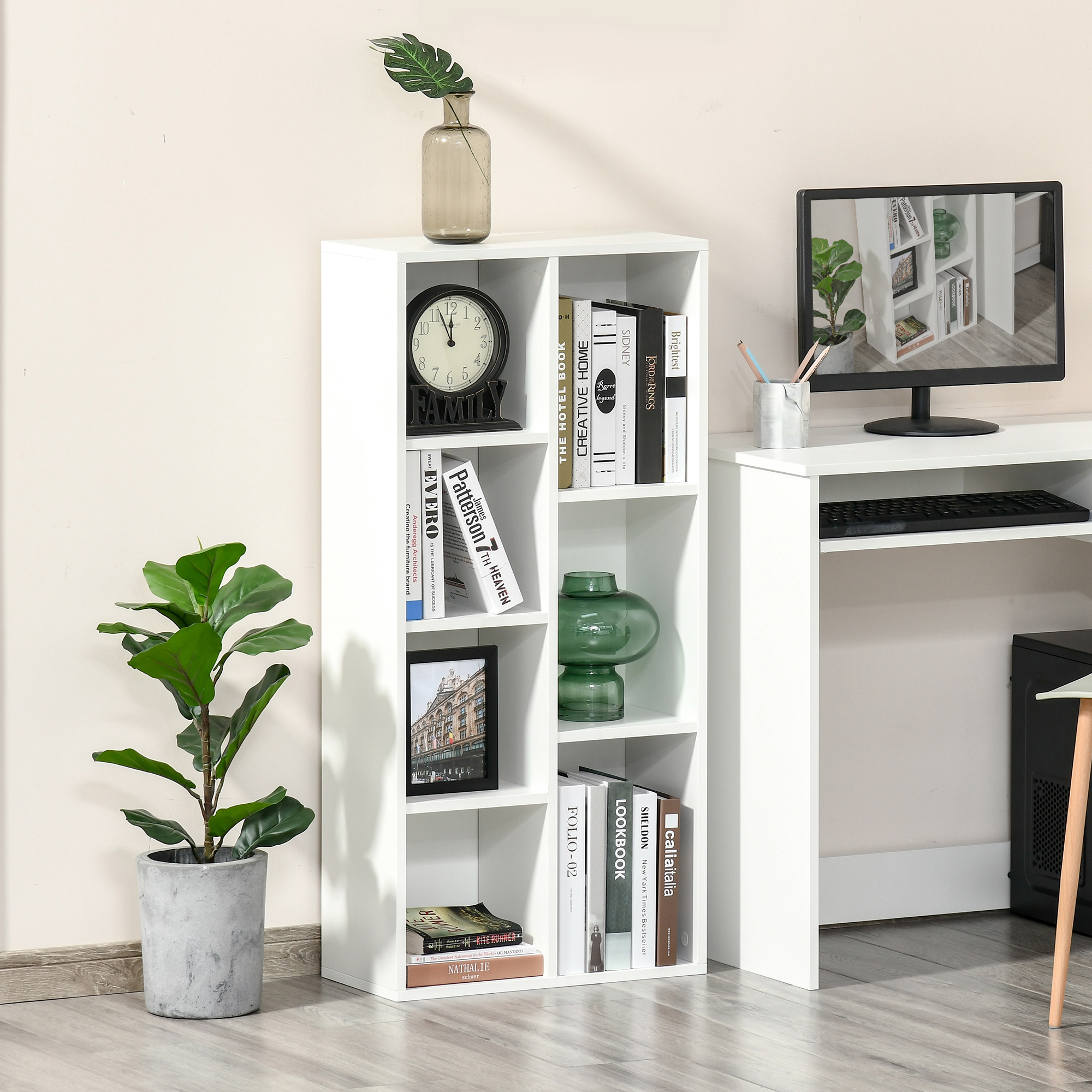 Estantería blanca con libros, reloj, jarrón, planta y cuadro enmarcado. Escritorio con monitor.
