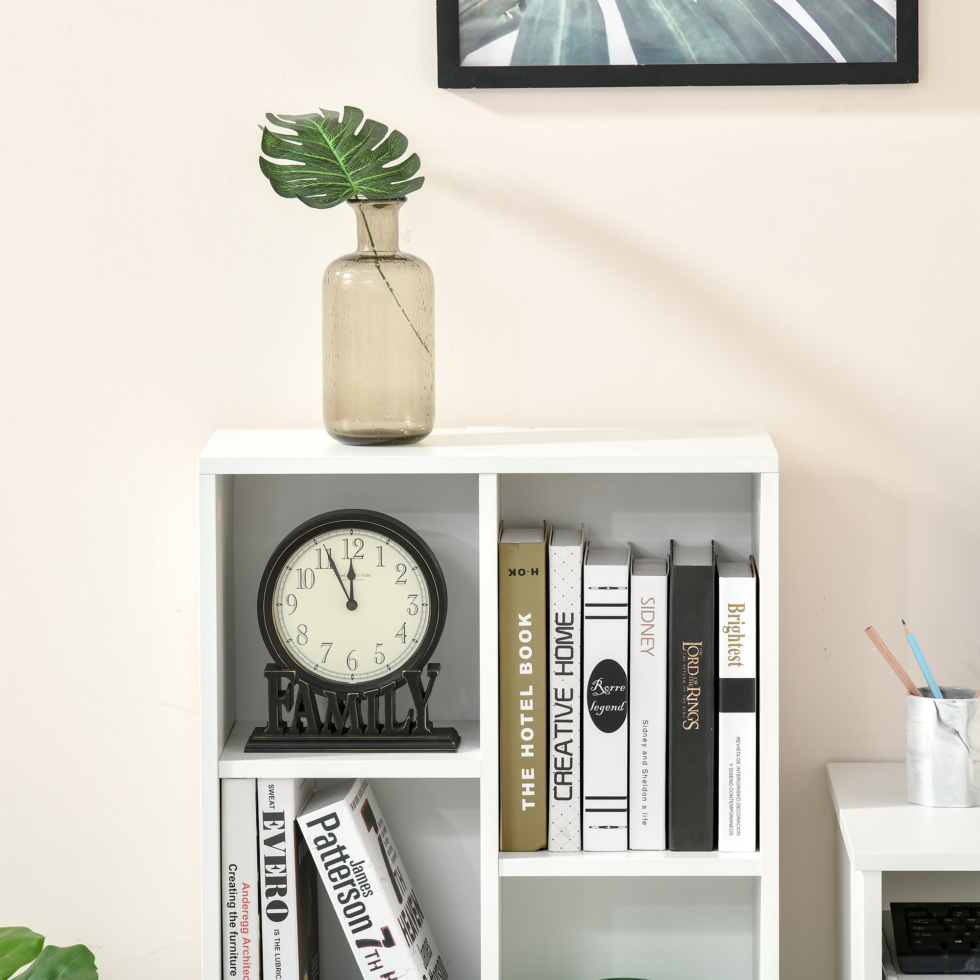 Una estantería con libros, un reloj y un jarrón con una planta.