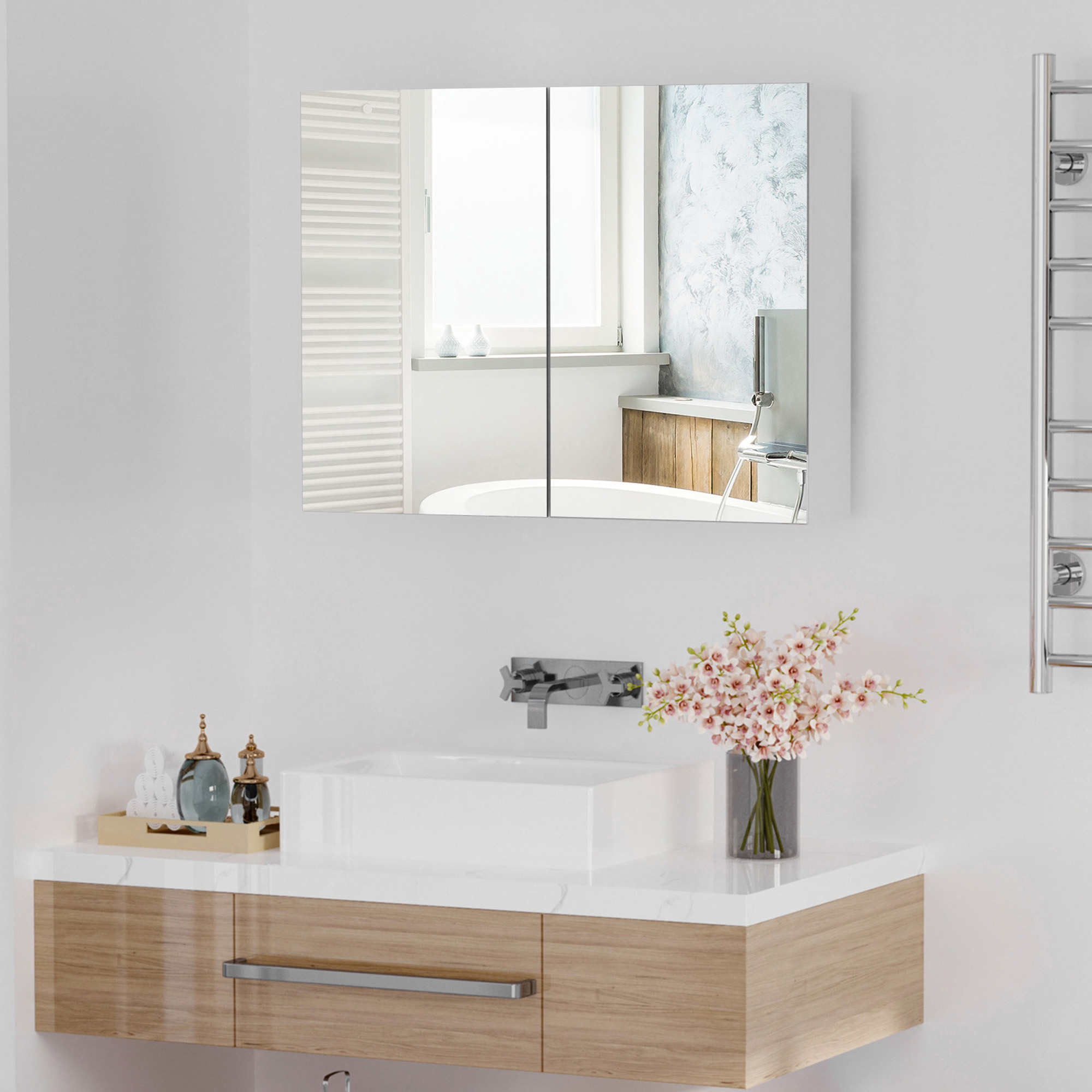 Baño con lavabo, espejo, bañera y toallero.