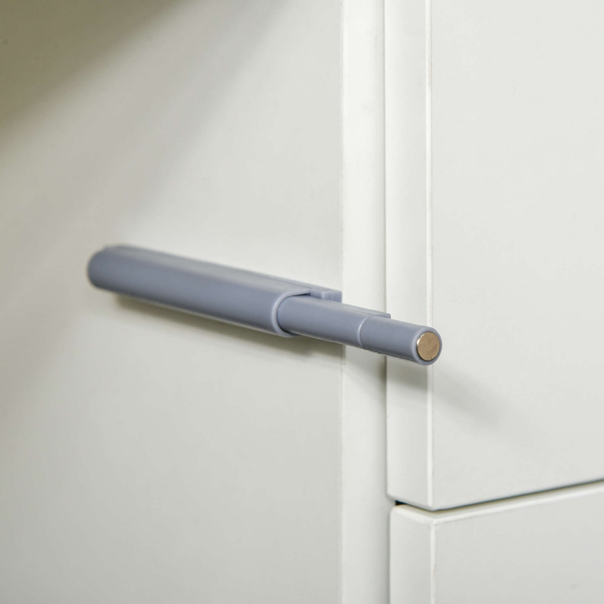 Un mecanismo gris de empujar para abrir en una puerta blanca.