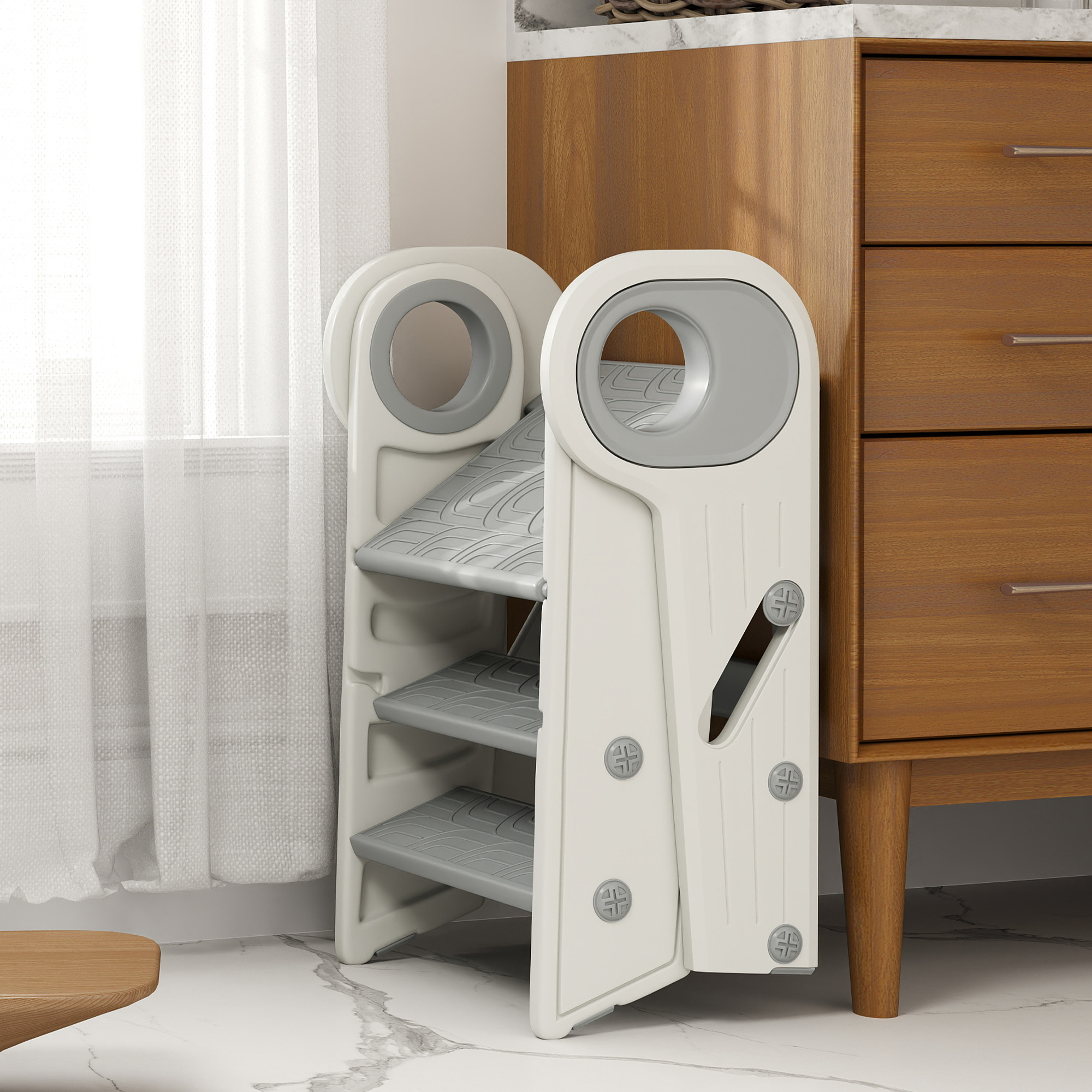 Un taburete plegable blanco con escalones grises junto a una cómoda de madera.
