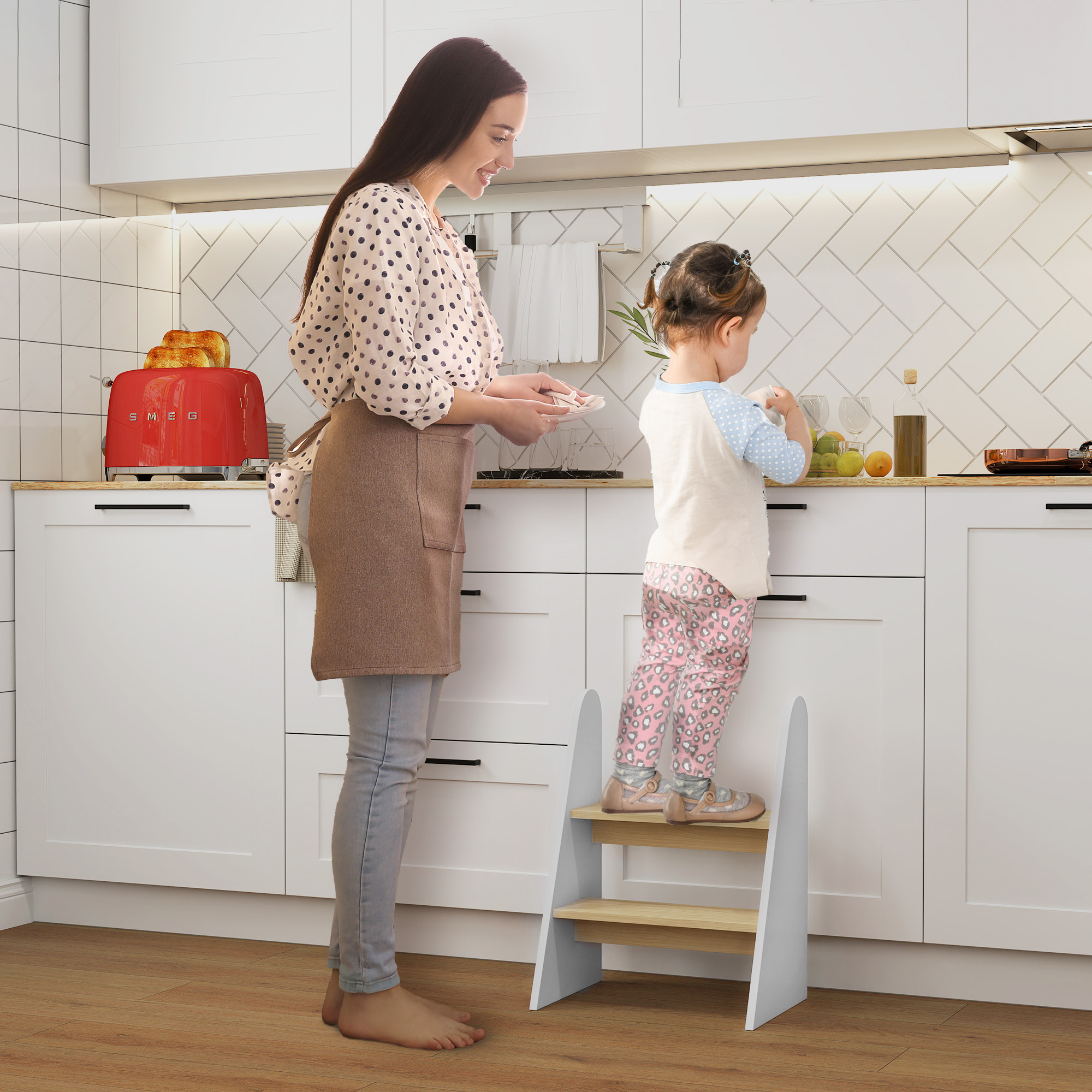 Madre e hija en la cocina. La hija está de pie en un taburete al lado de la madre.