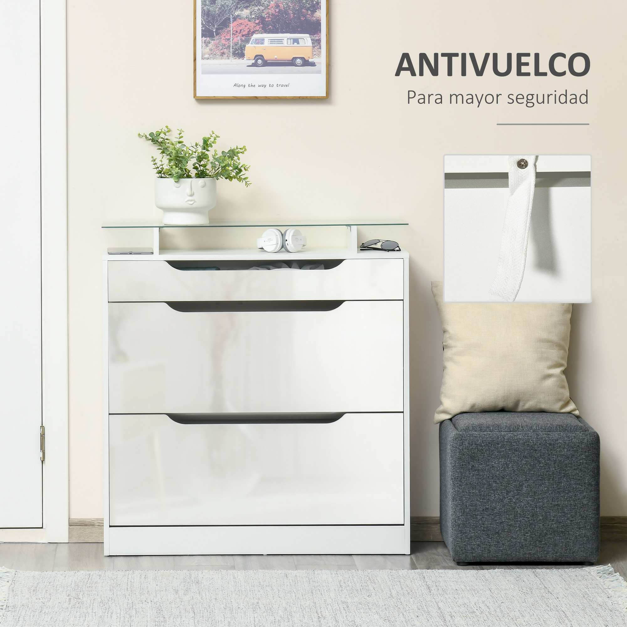 Cómoda blanca con estante de vidrio, planta y cuadro encima. Un otomano gris con cojín está cerca.