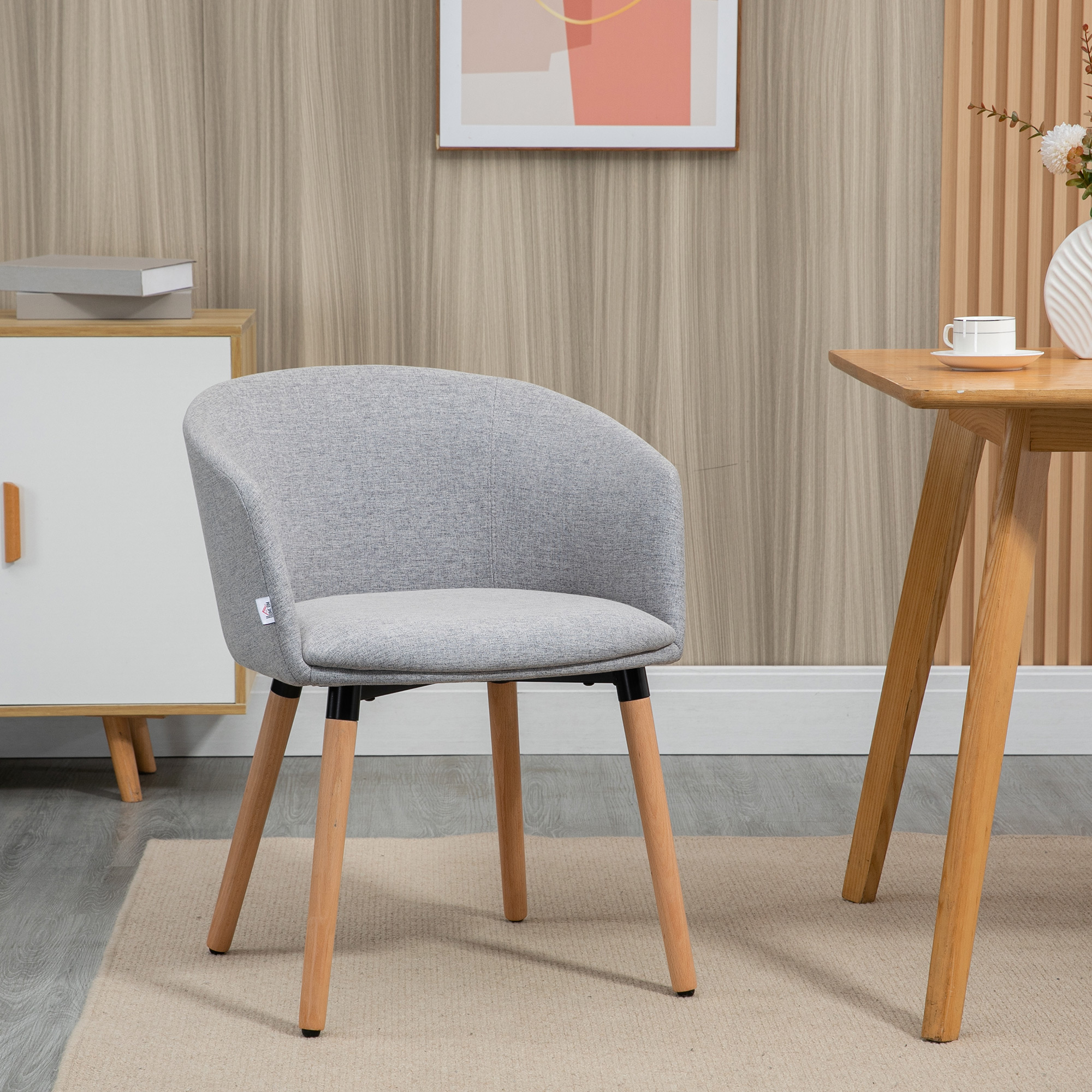 Silla gris de tela con patas de madera junto a mesa de madera con taza.