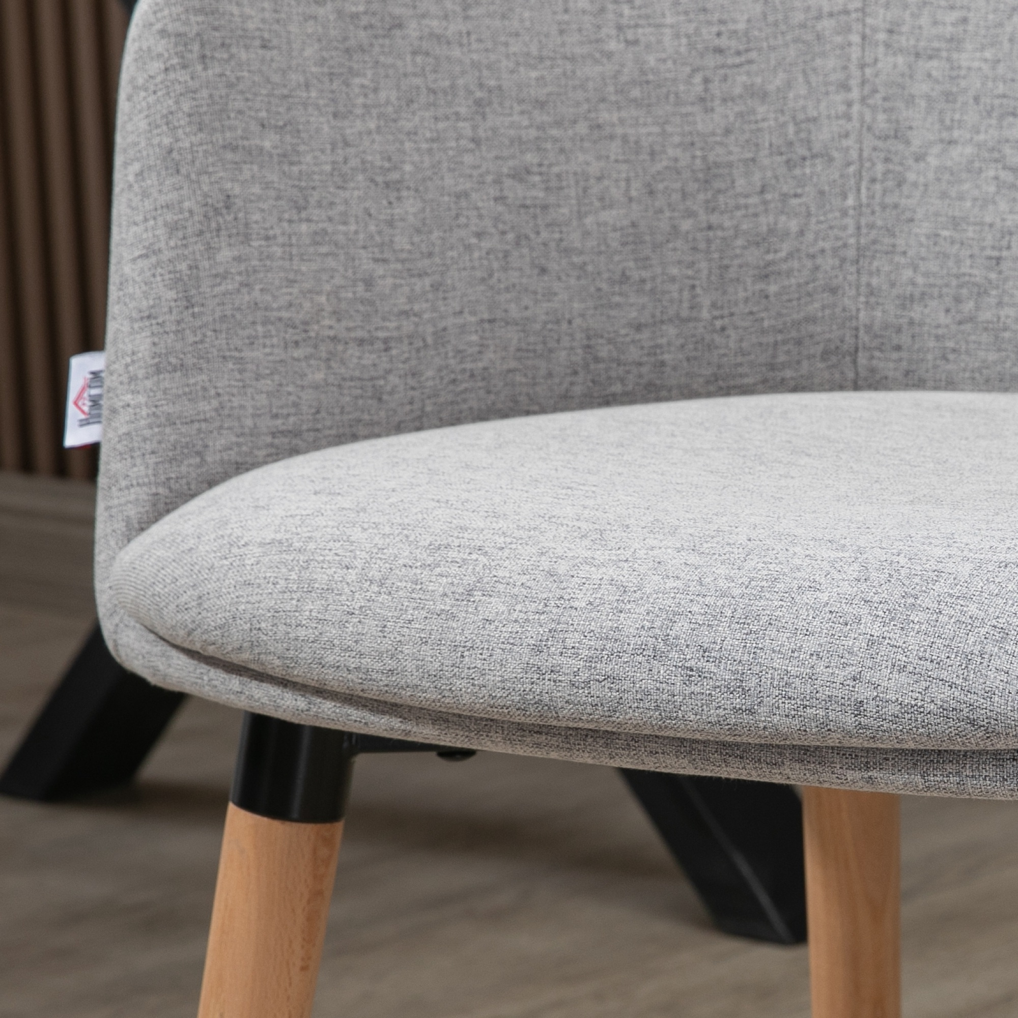 Silla de tela gris con patas de madera y marco de metal negro.