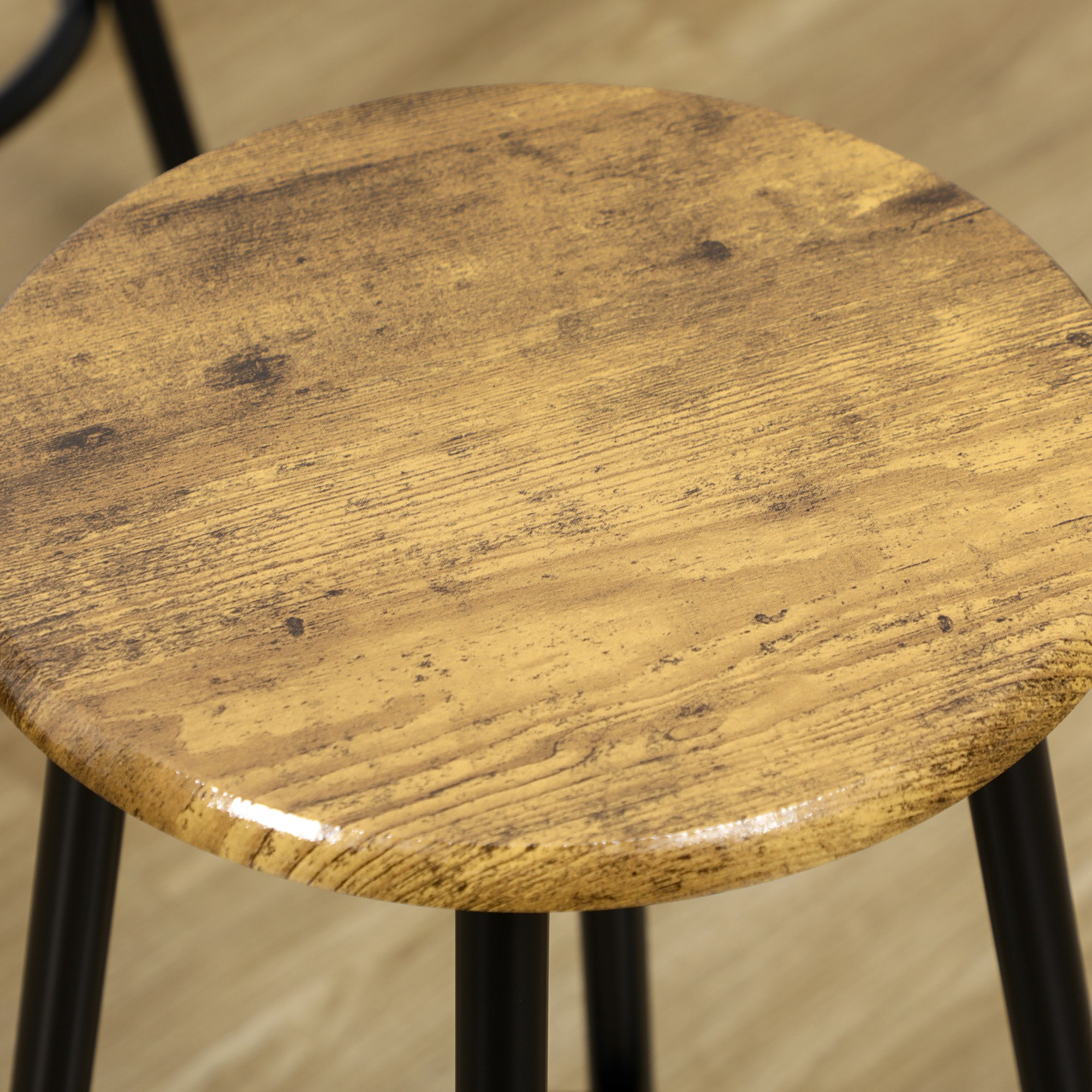 Superficie redonda de madera con patas de metal negro sobre suelo de madera.