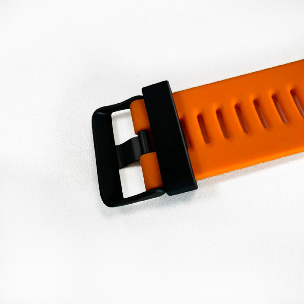Ein orangefarbenes Armband mit schwarzer Schnalle auf weißem Hintergrund.
