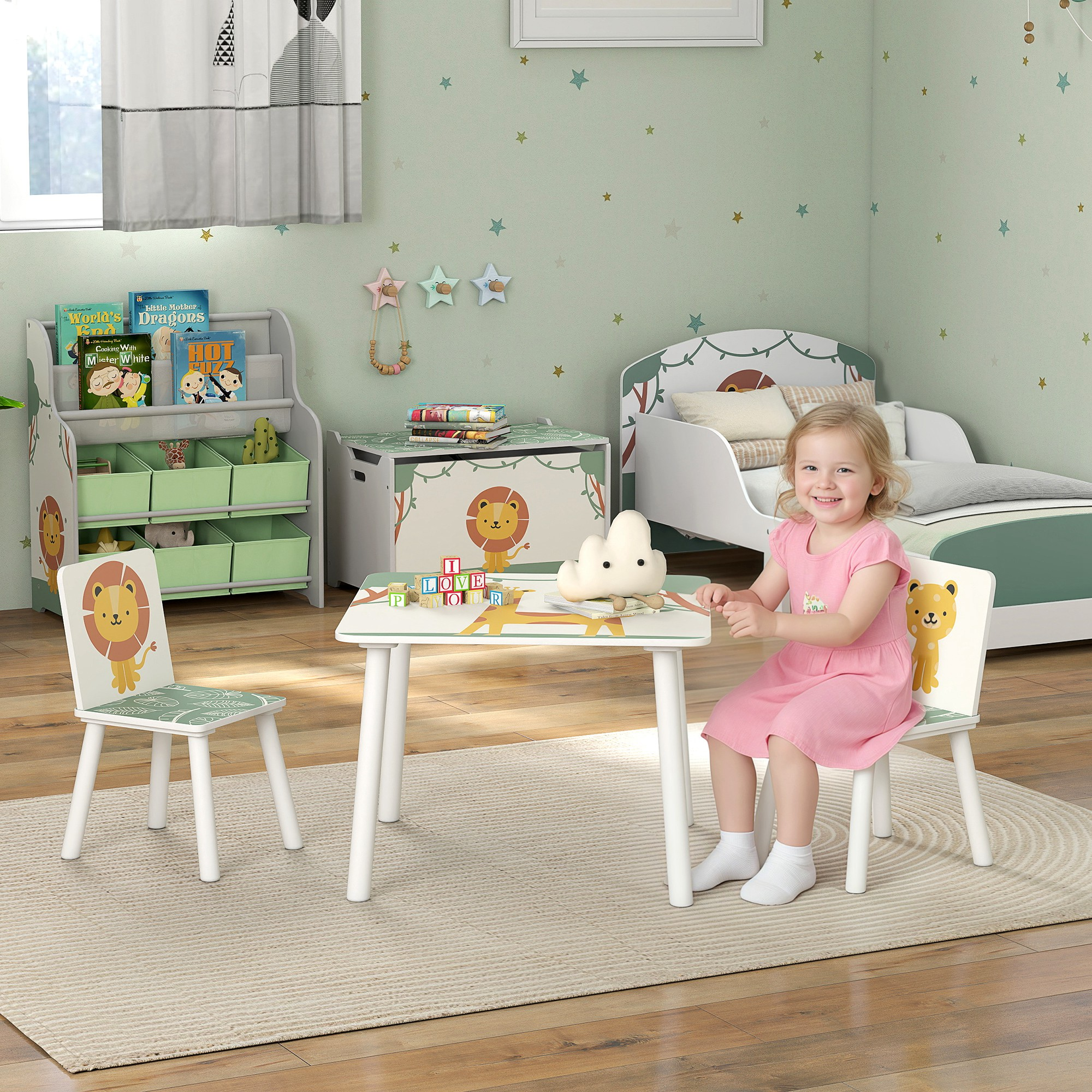 Una bambina siede a un tavolino per bambini a tema leone in una stanza verde chiaro.