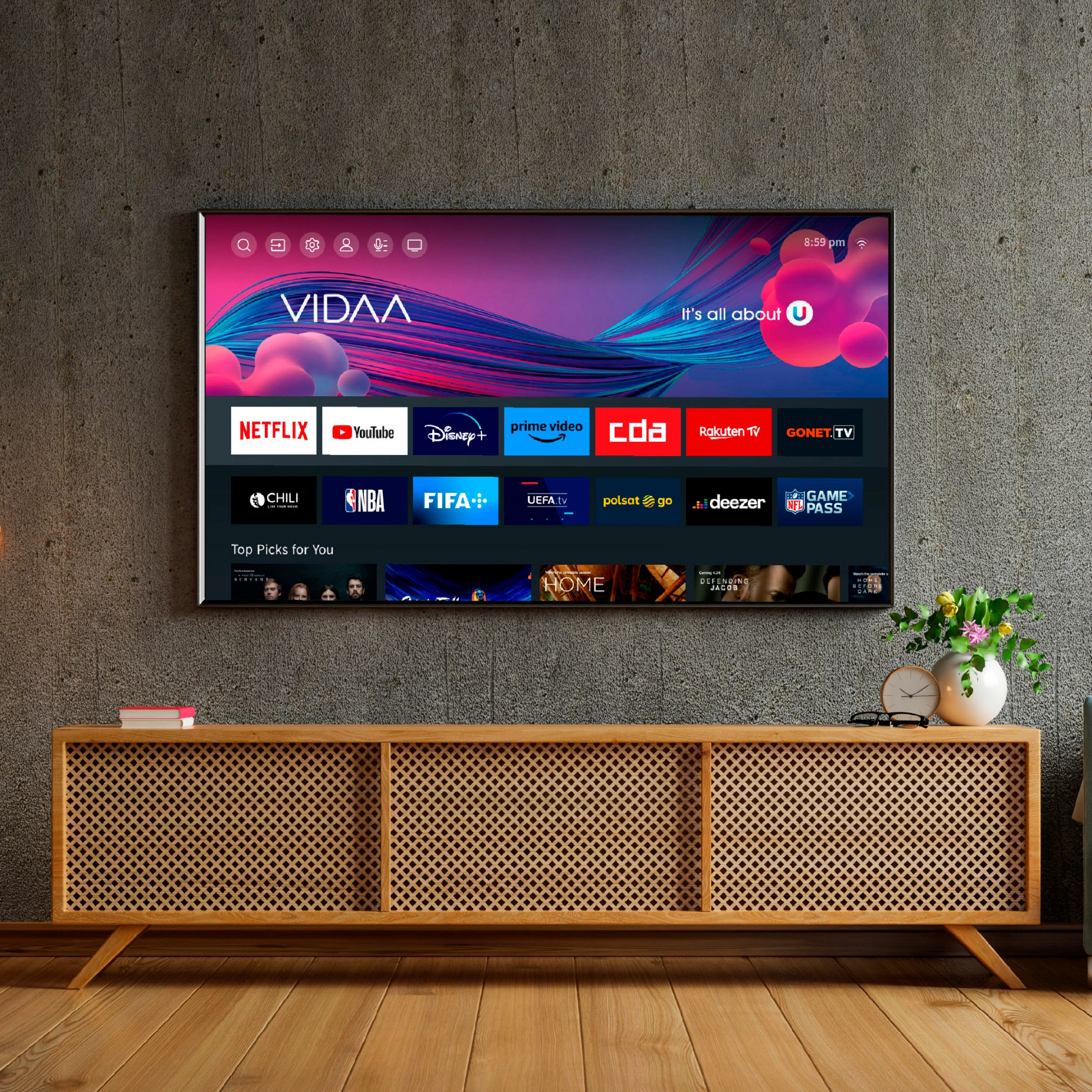 Ein moderner Fernseher zeigt die VIDAA-Oberfläche mit App-Logos. Unten steht ein Holzschrank.