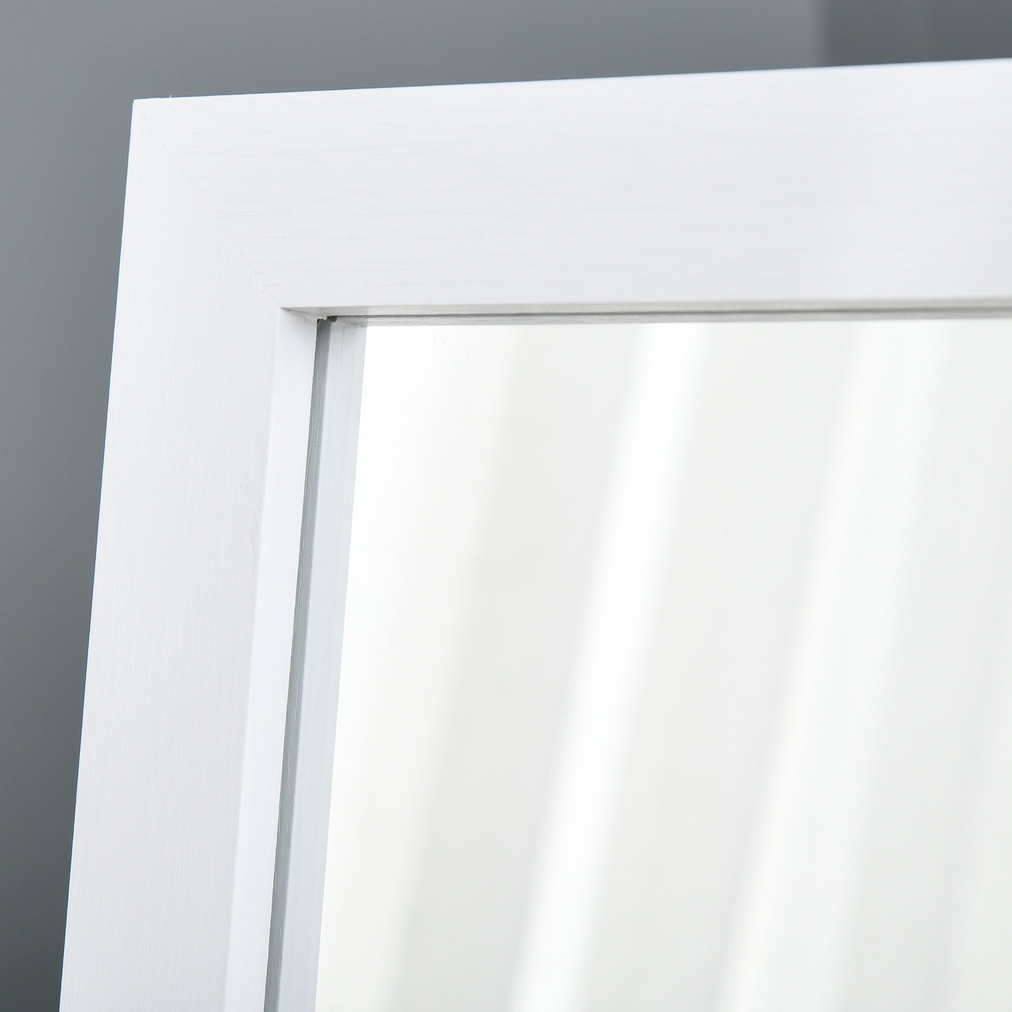Primer plano de un marco de espejo blanco con pared gris al fondo.