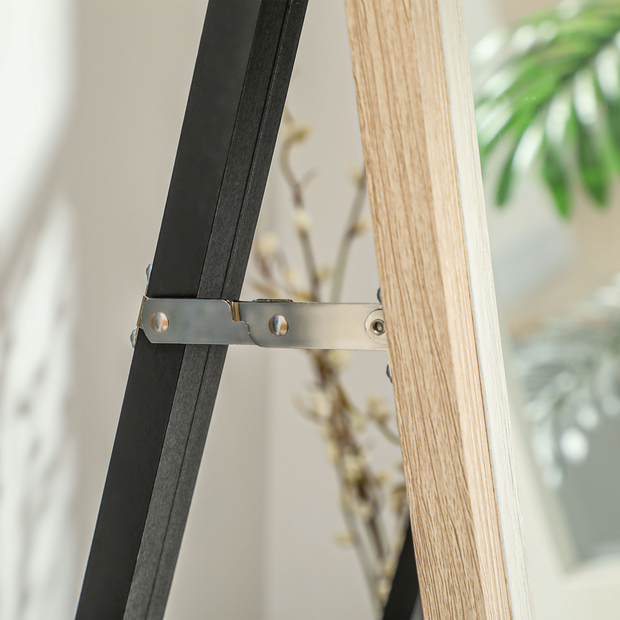 Primer plano de una bisagra metálica que une marcos negros y de madera.