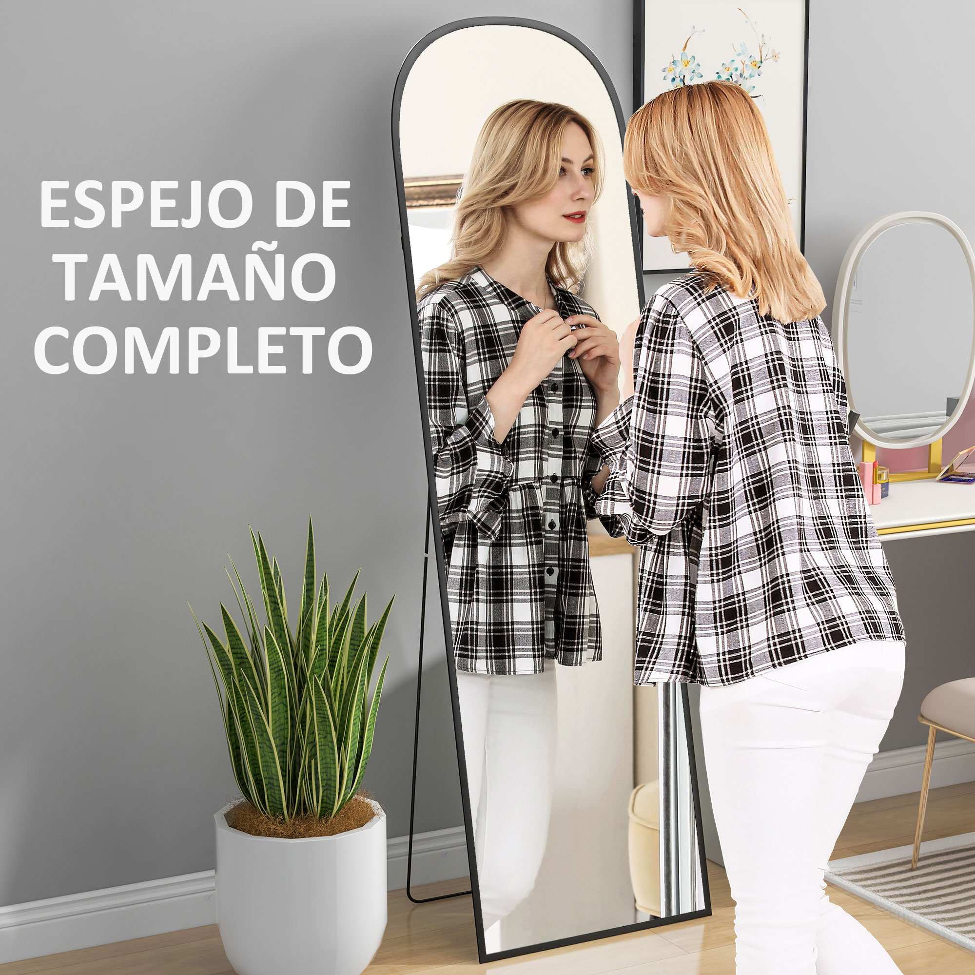 Mujer con camisa a cuadros frente a un espejo ovalado. Una planta a la izquierda.
