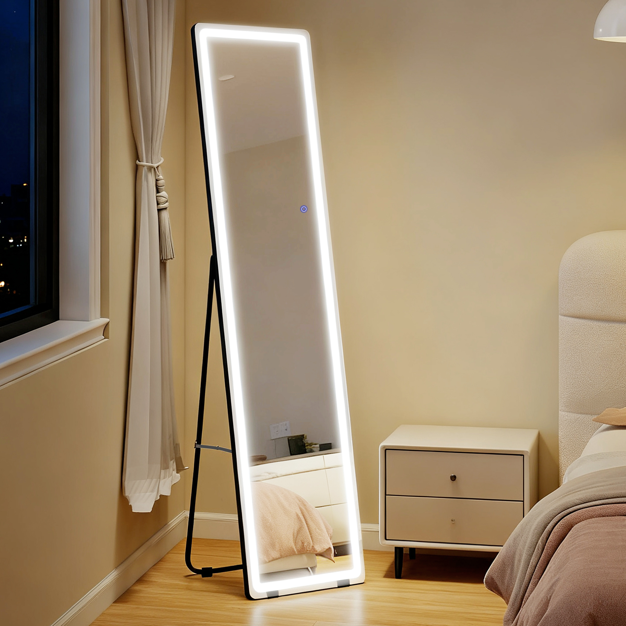 Un espejo de cuerpo entero con iluminación integrada y marco negro junto a una mesita de noche.