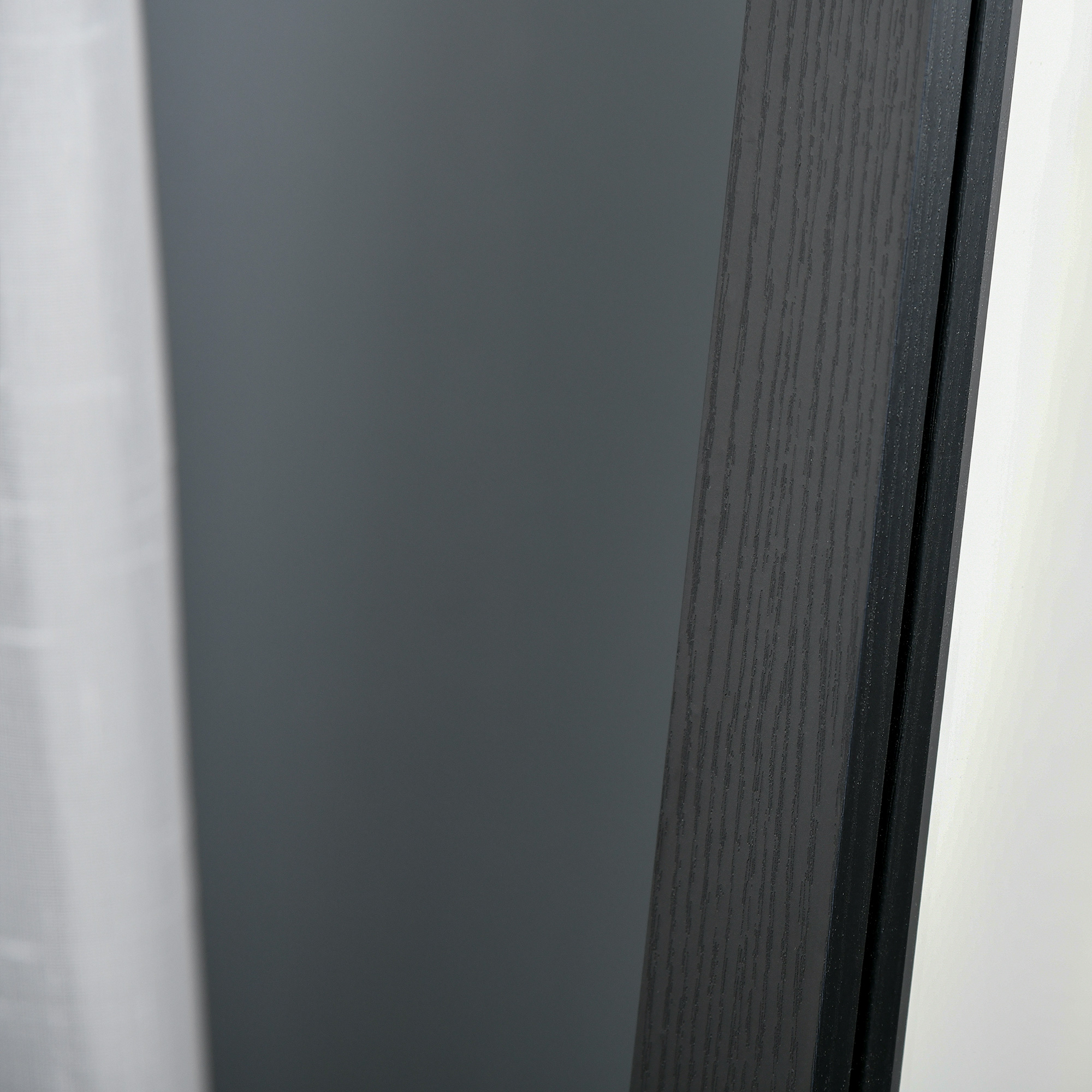 Puerta gris oscuro con veta de madera y cortina blanca.