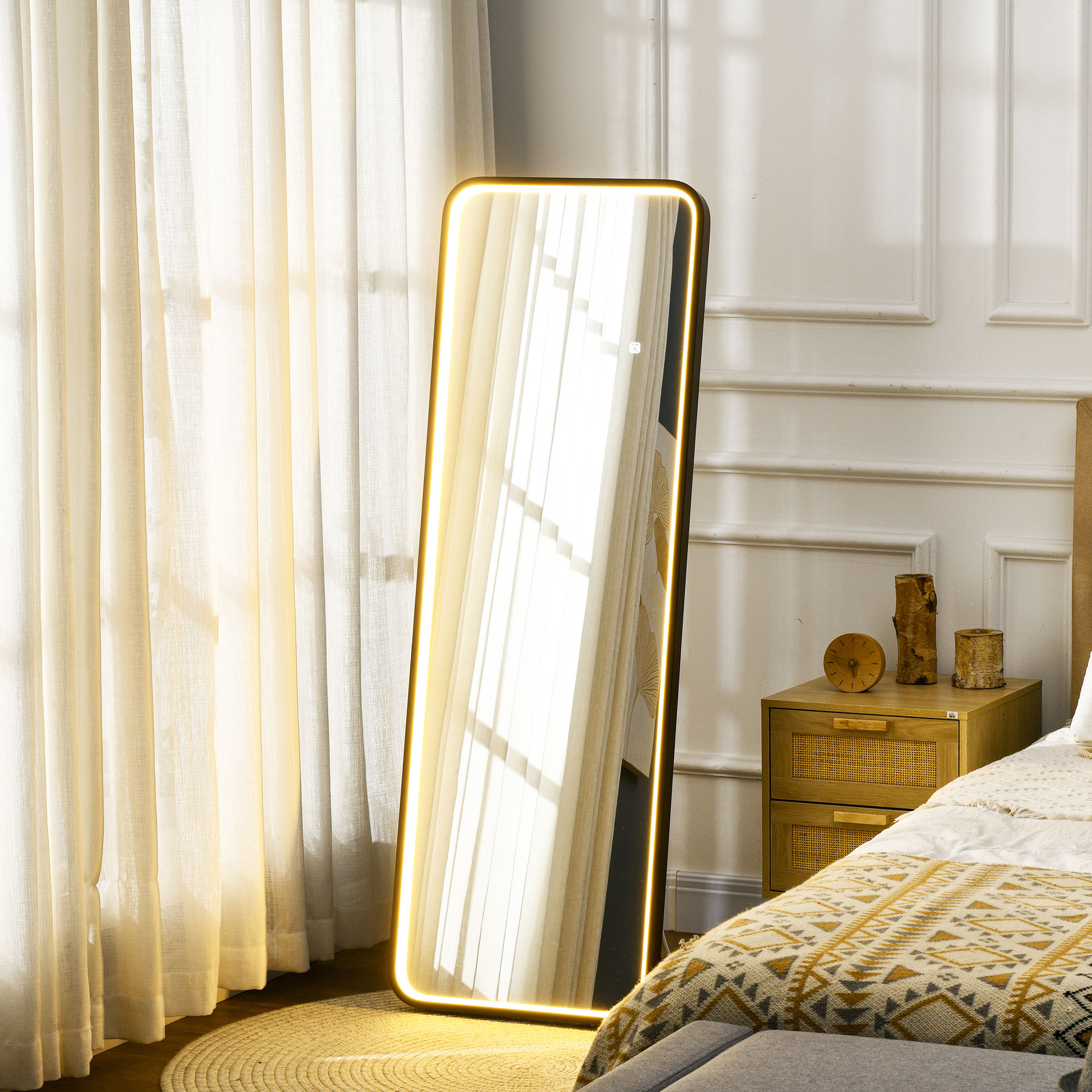 Un espejo iluminado junto a una mesita de noche con ropa de cama y cortinas.