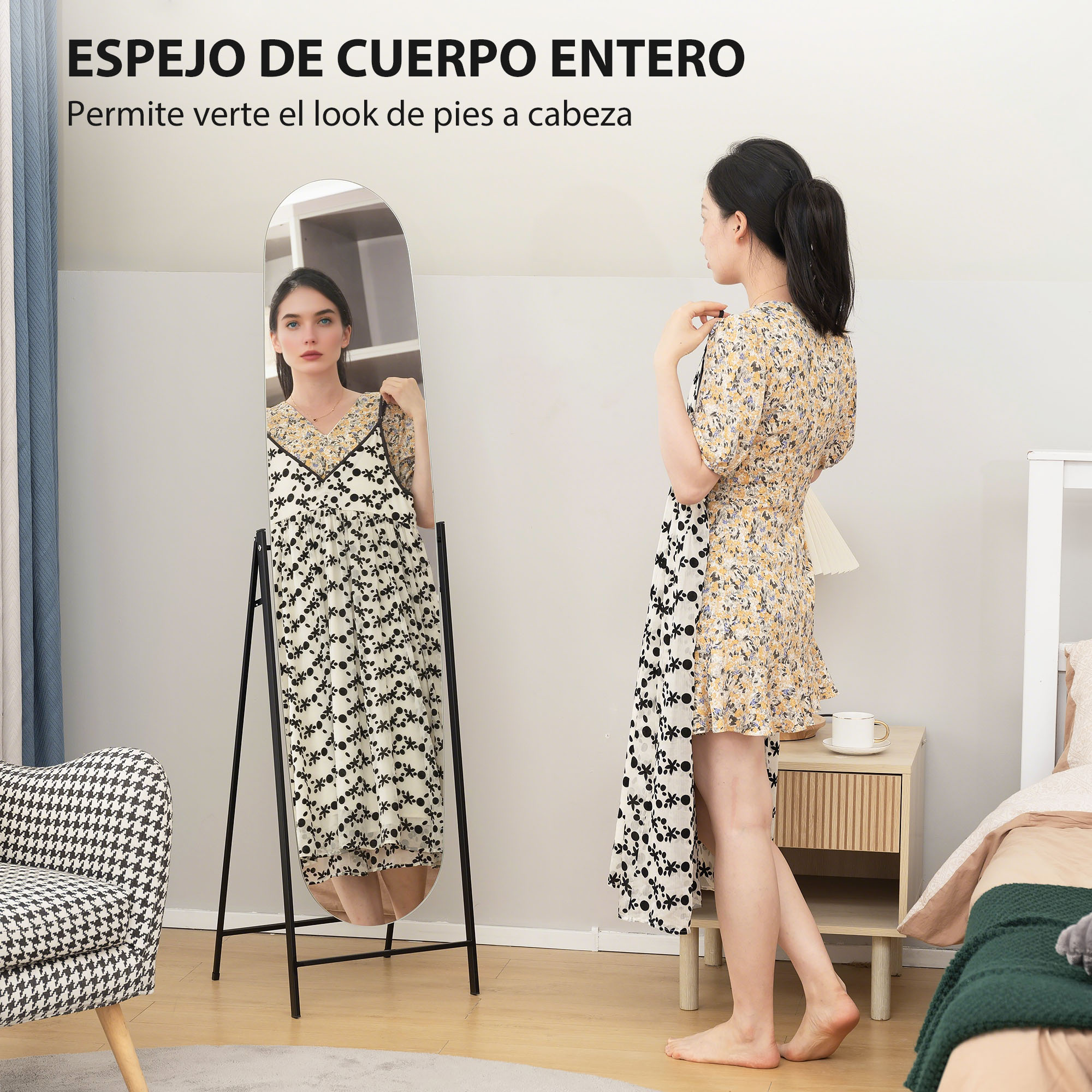 Una mujer con vestido estampado frente a un espejo de cuerpo entero. Un sillón a la izquierda.
