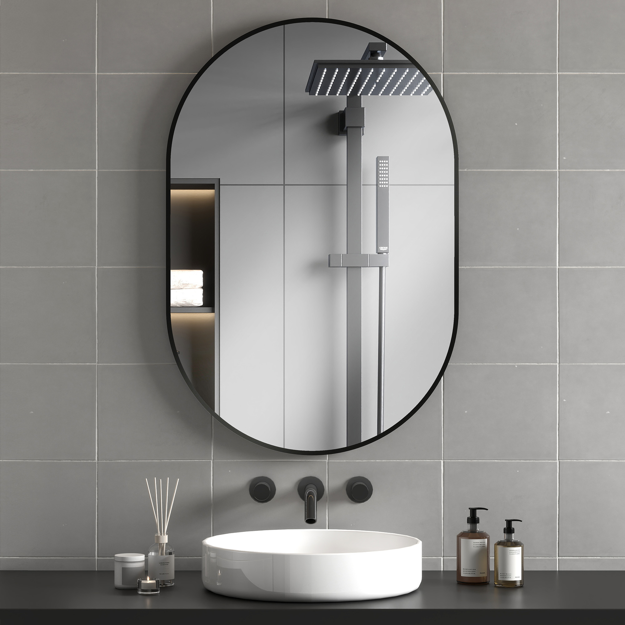 Un tocador de baño moderno con espejo ovalado, lavabo y dos dispensadores de jabón.