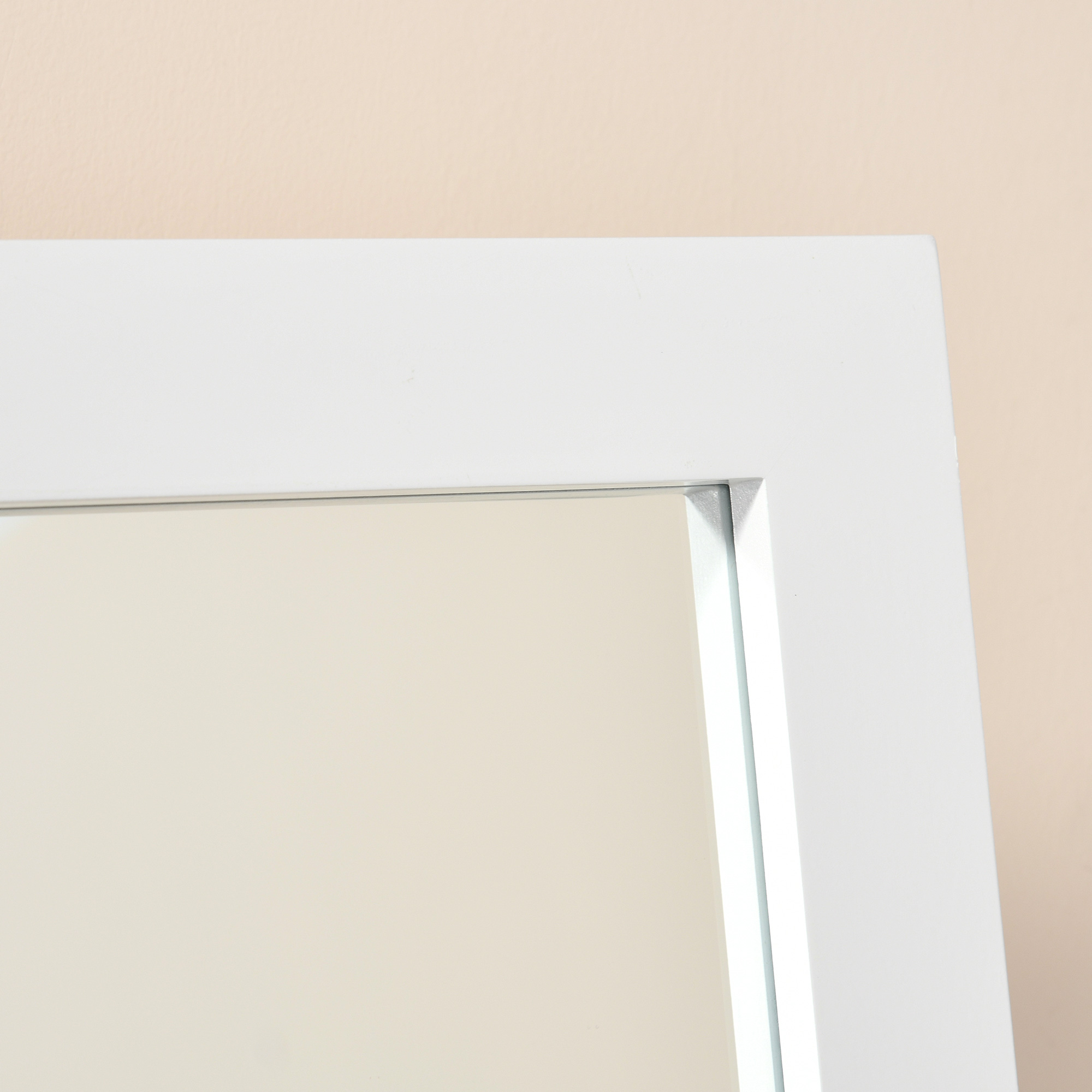 Un marco de espejo blanco contra un fondo color crema.