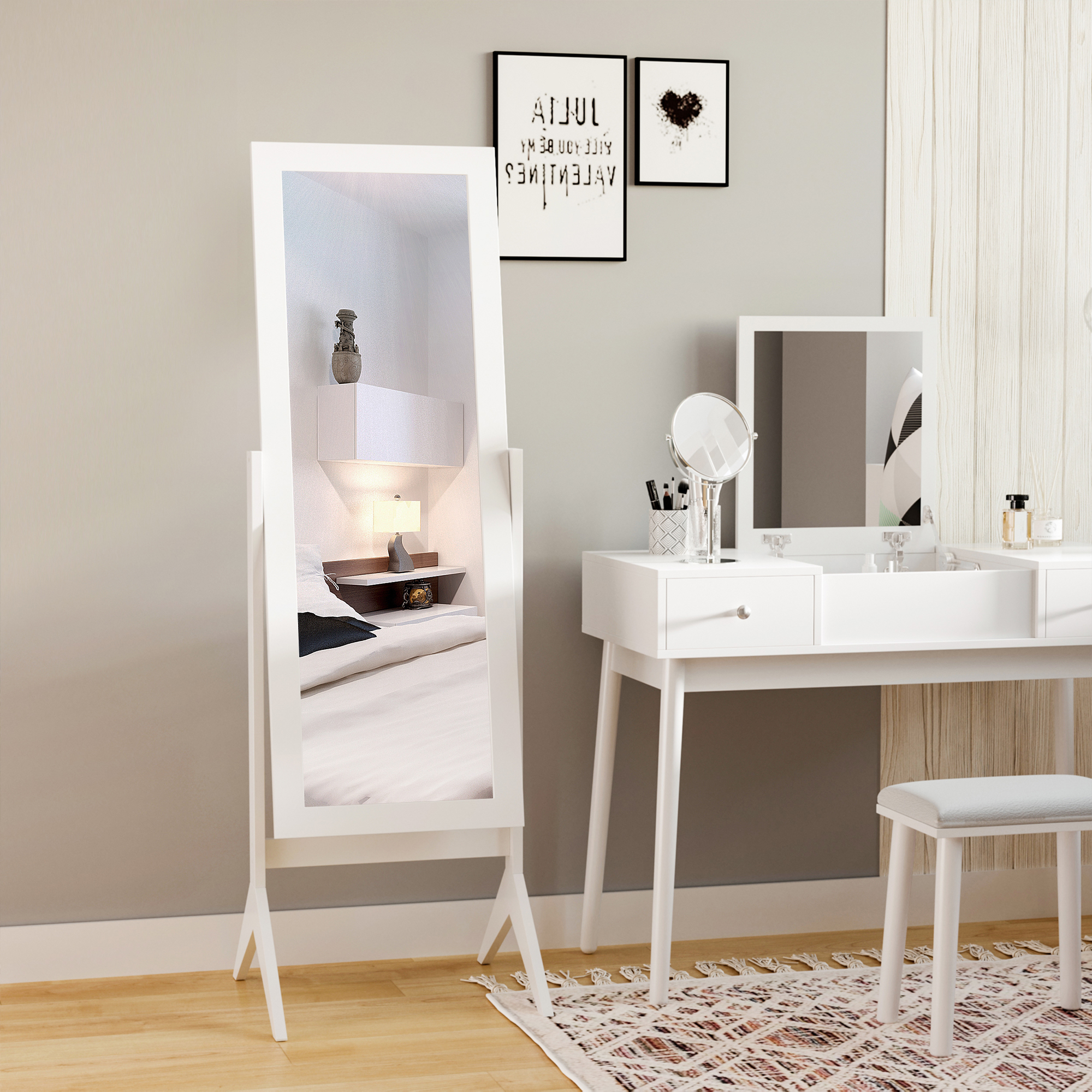 Un espejo de cuerpo entero blanco refleja una cama. Un tocador blanco con espejo, taburete y decoración.