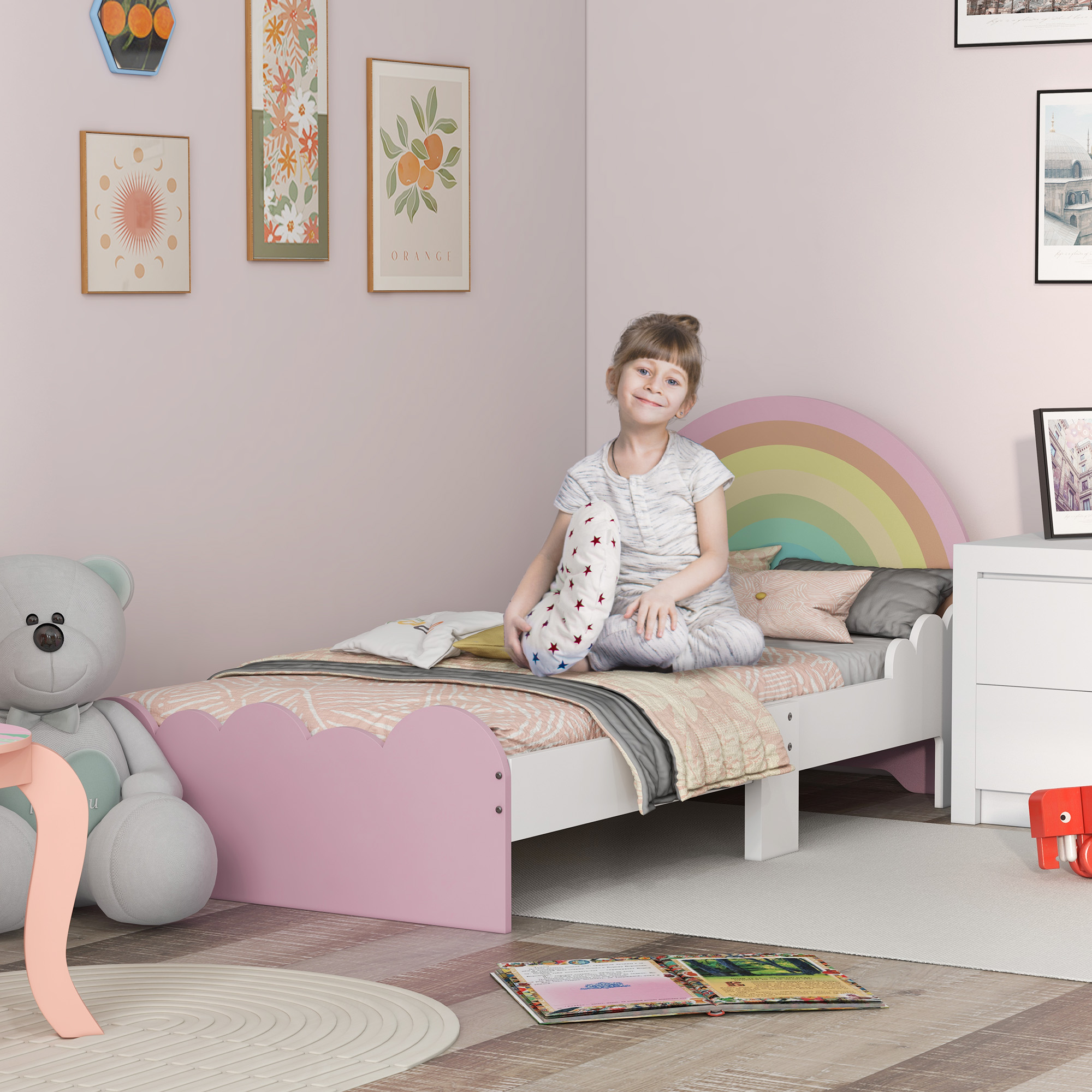 Una niña se sienta en una cama con cabecero de arcoíris. Un osito de peluche a la izquierda.