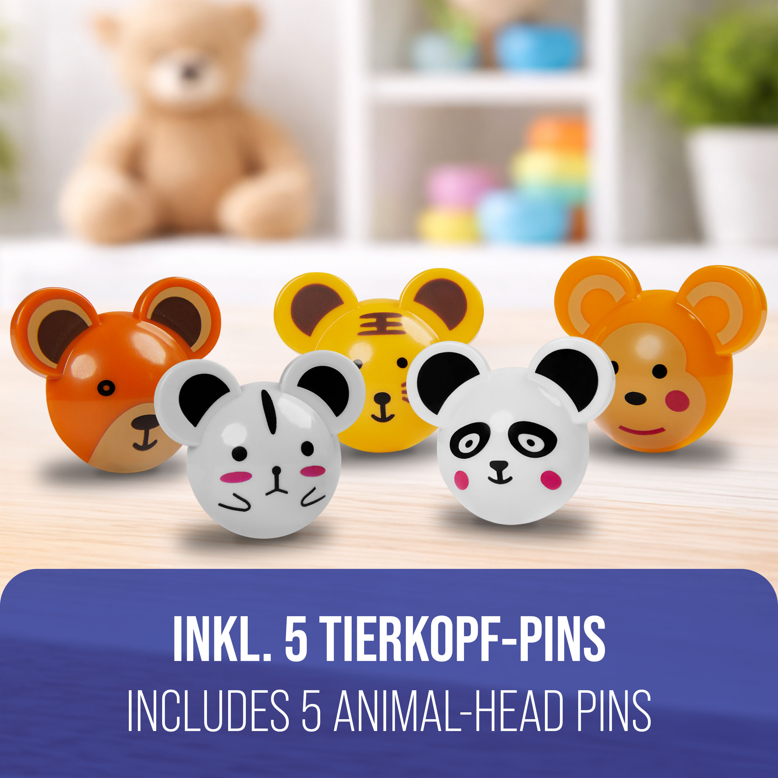 Fünf bunte Tierkopf-Pins auf Holzoberfläche, Teddy im Hintergrund.