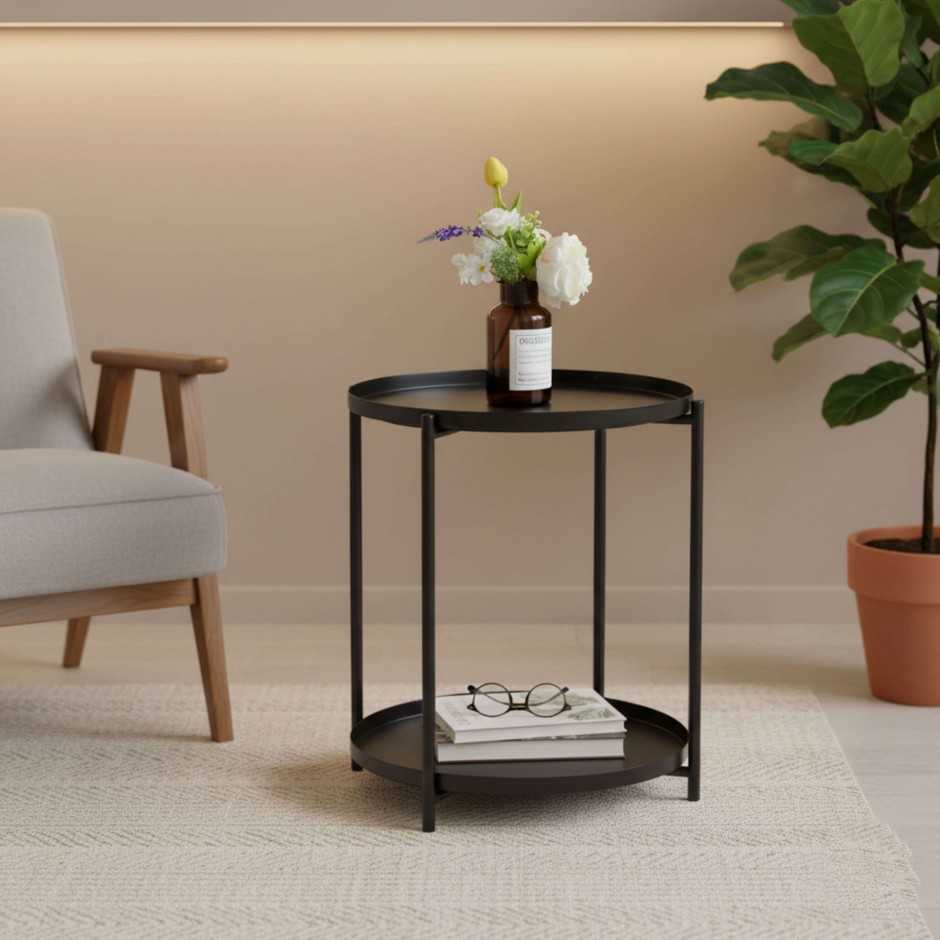 Una mesa auxiliar negra con flores y libros se encuentra junto a un sillón.
