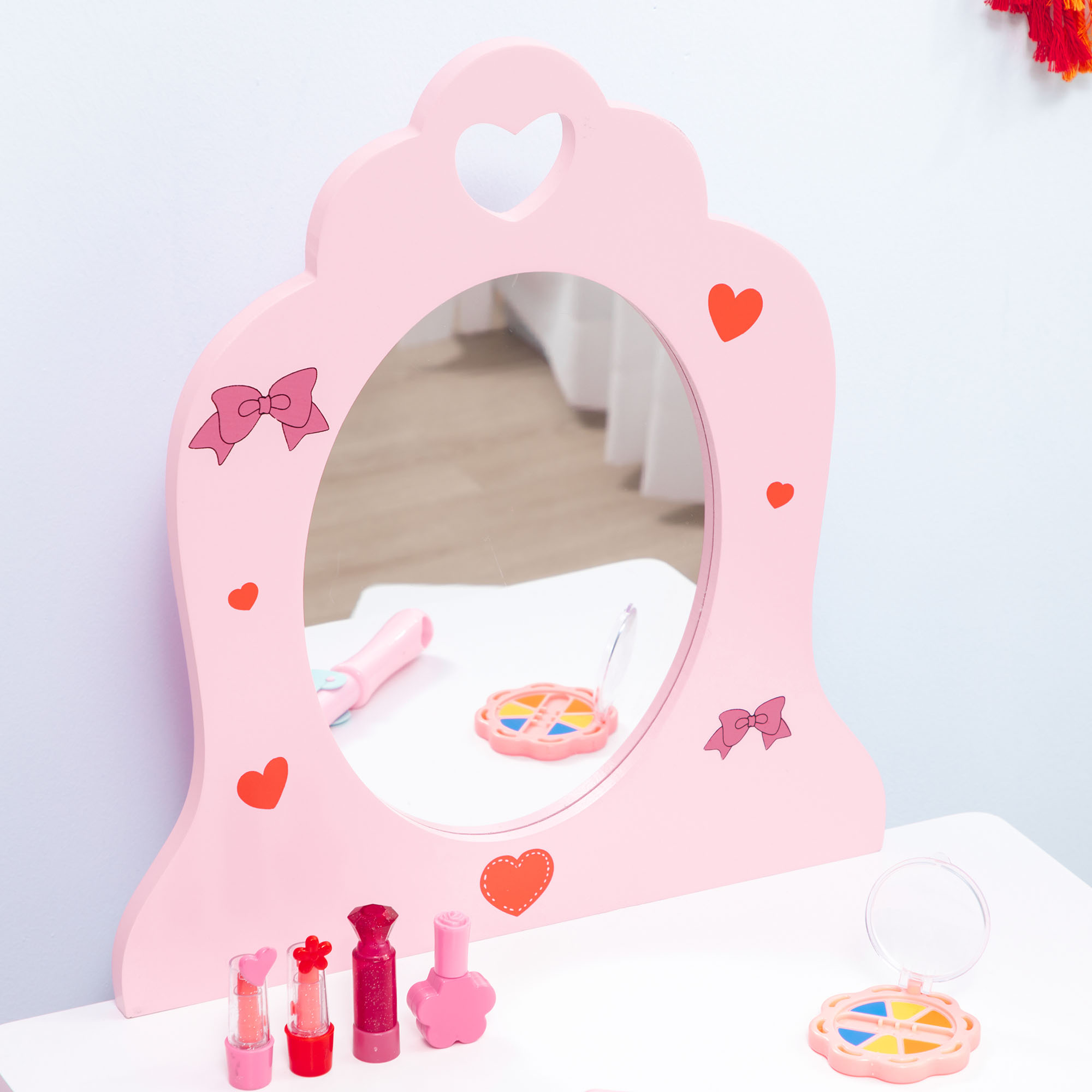 Un tocador rosa con cosméticos de juguete, lápices labiales y paleta de sombras.