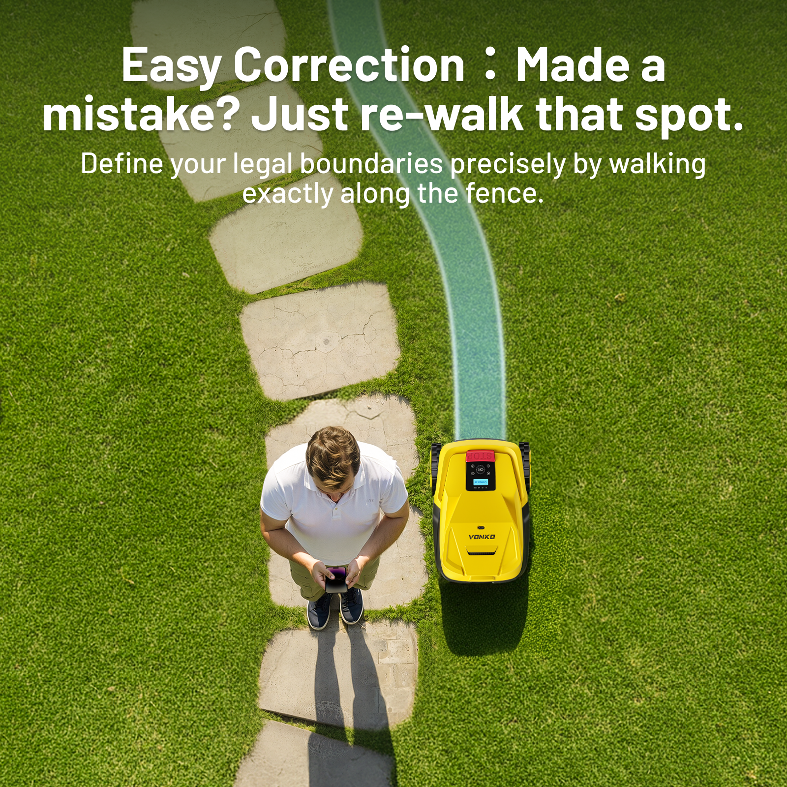 Mężczyzna ze smartfonem stoi obok żółtego robota koszącego na kamiennej ścieżce.