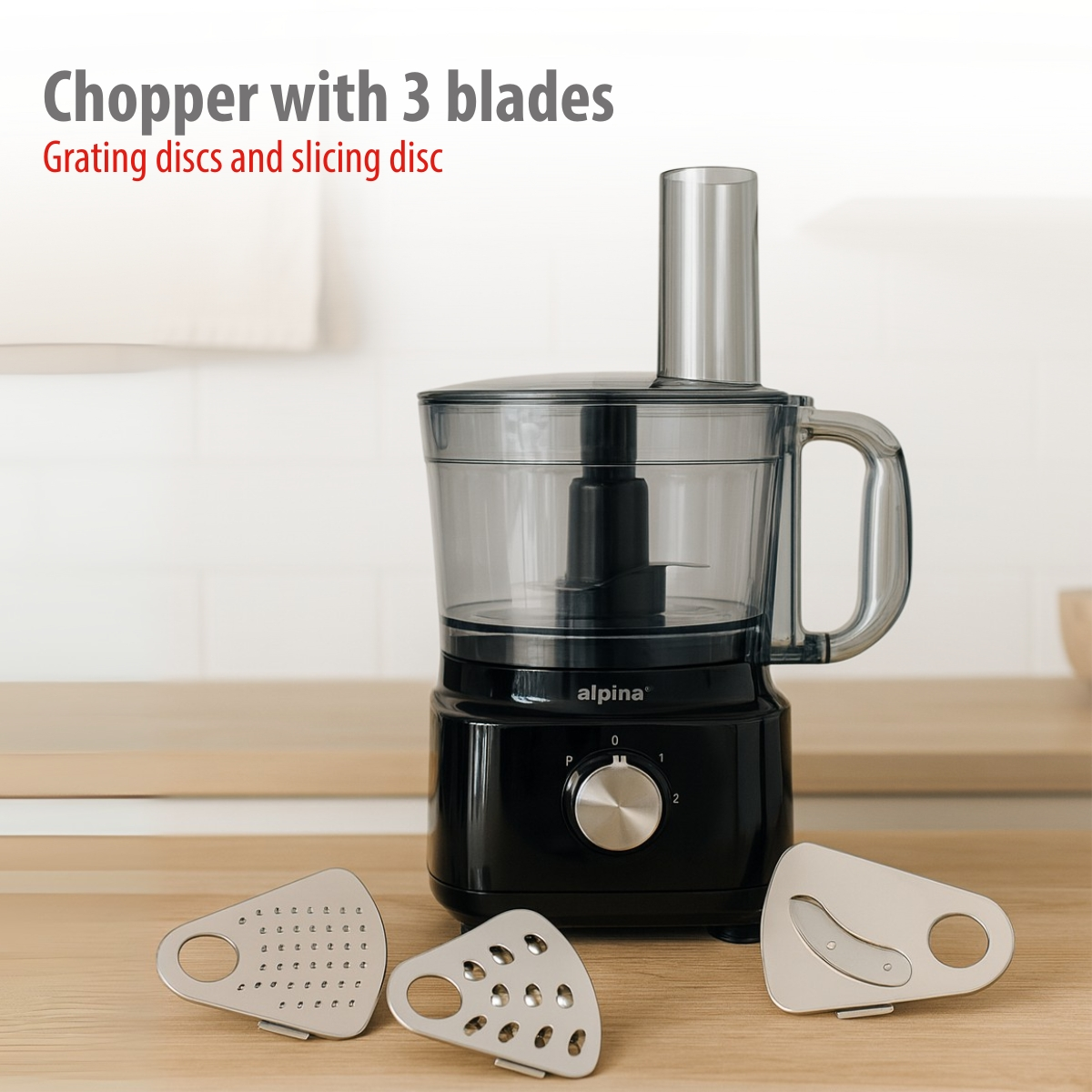 Black food processor with transparent bowl and three blades. Three discs in front.