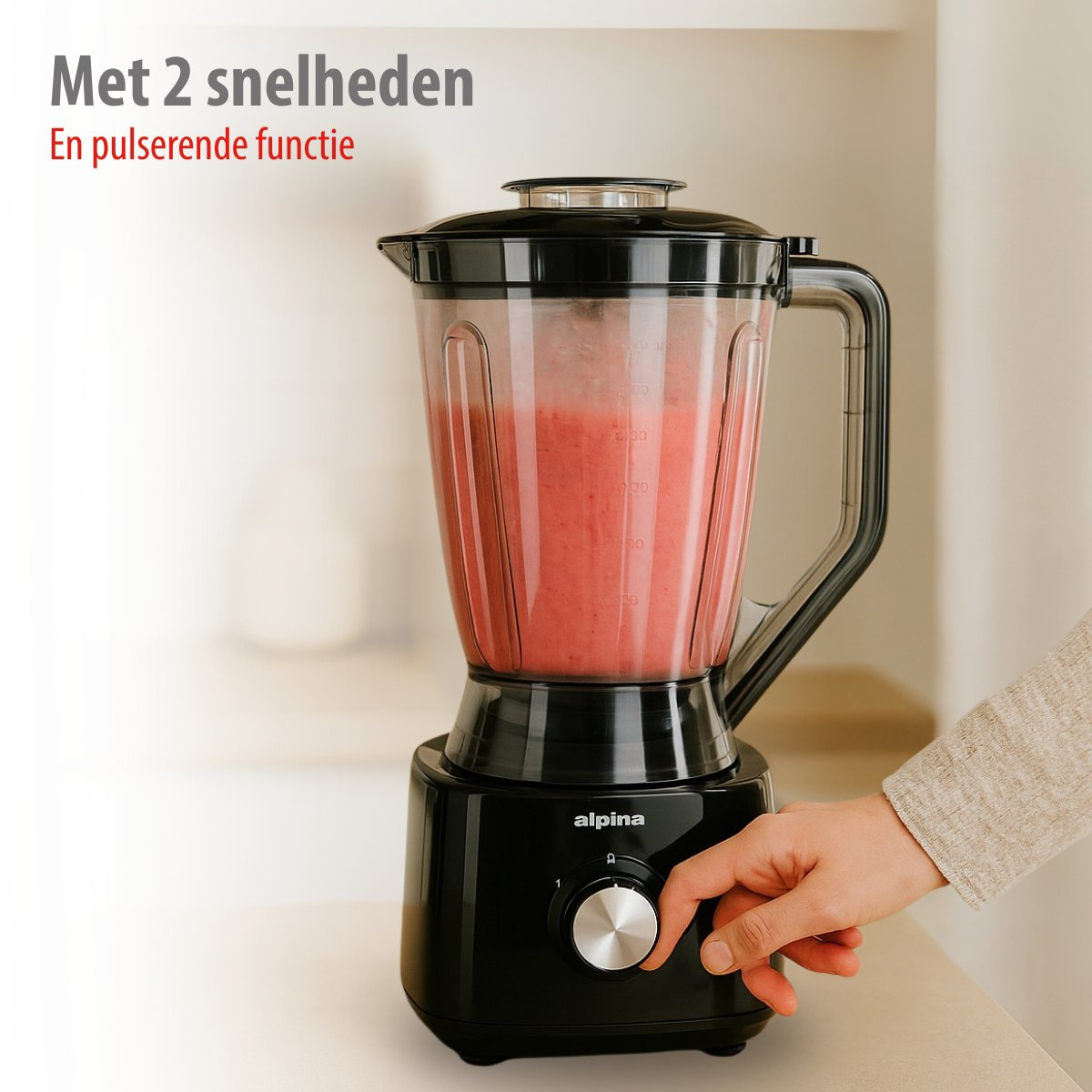 A black blender with pink smoothie. A hand turns the knob.