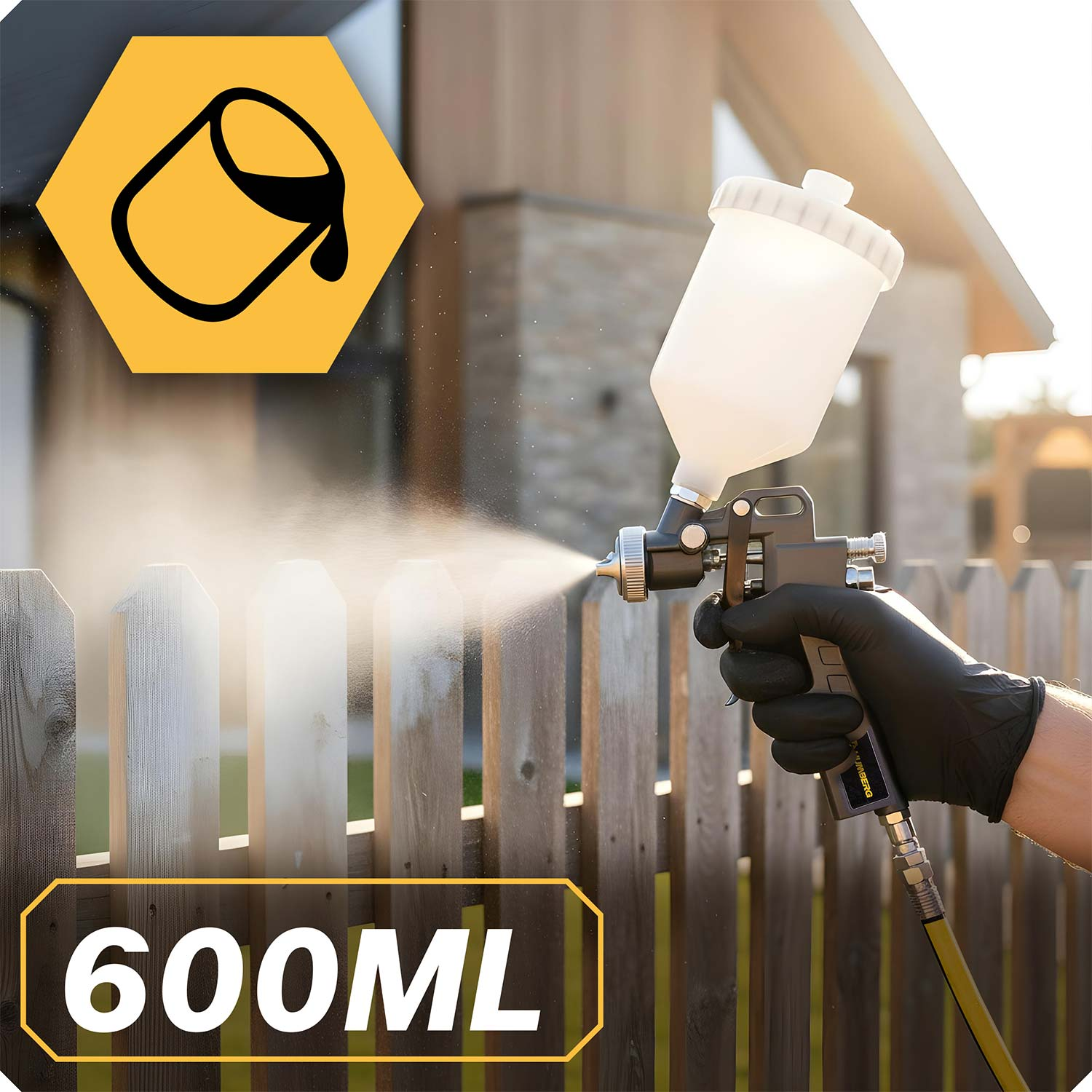 Ręka w rękawiczce natryskuje drewniany płot pistoletem natryskowym.